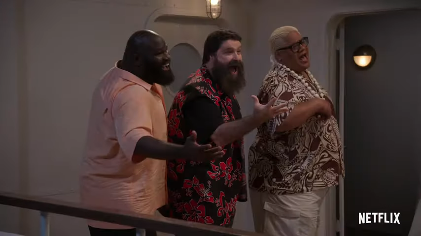Three men standing together indoors, laughing and enjoying conversation, with one gesturing with his hands.