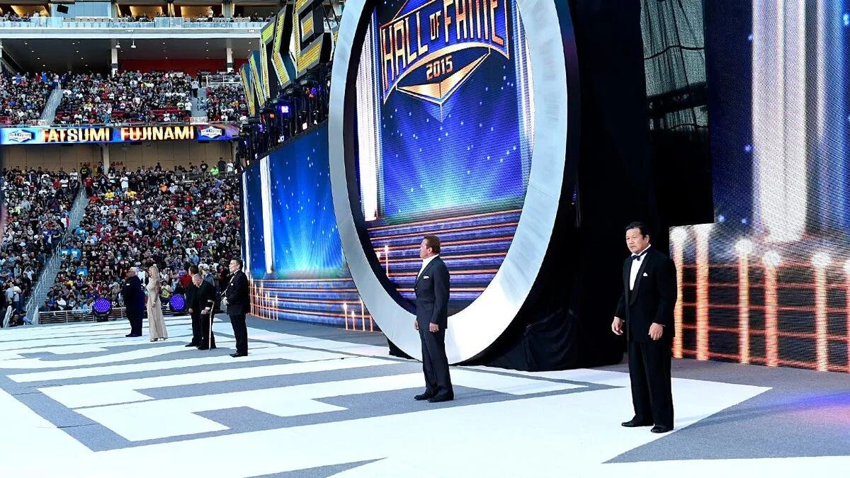People in tuxedos standing on stage at the 2015 Hall of Fame induction ceremony in a stadium filled with audience members.