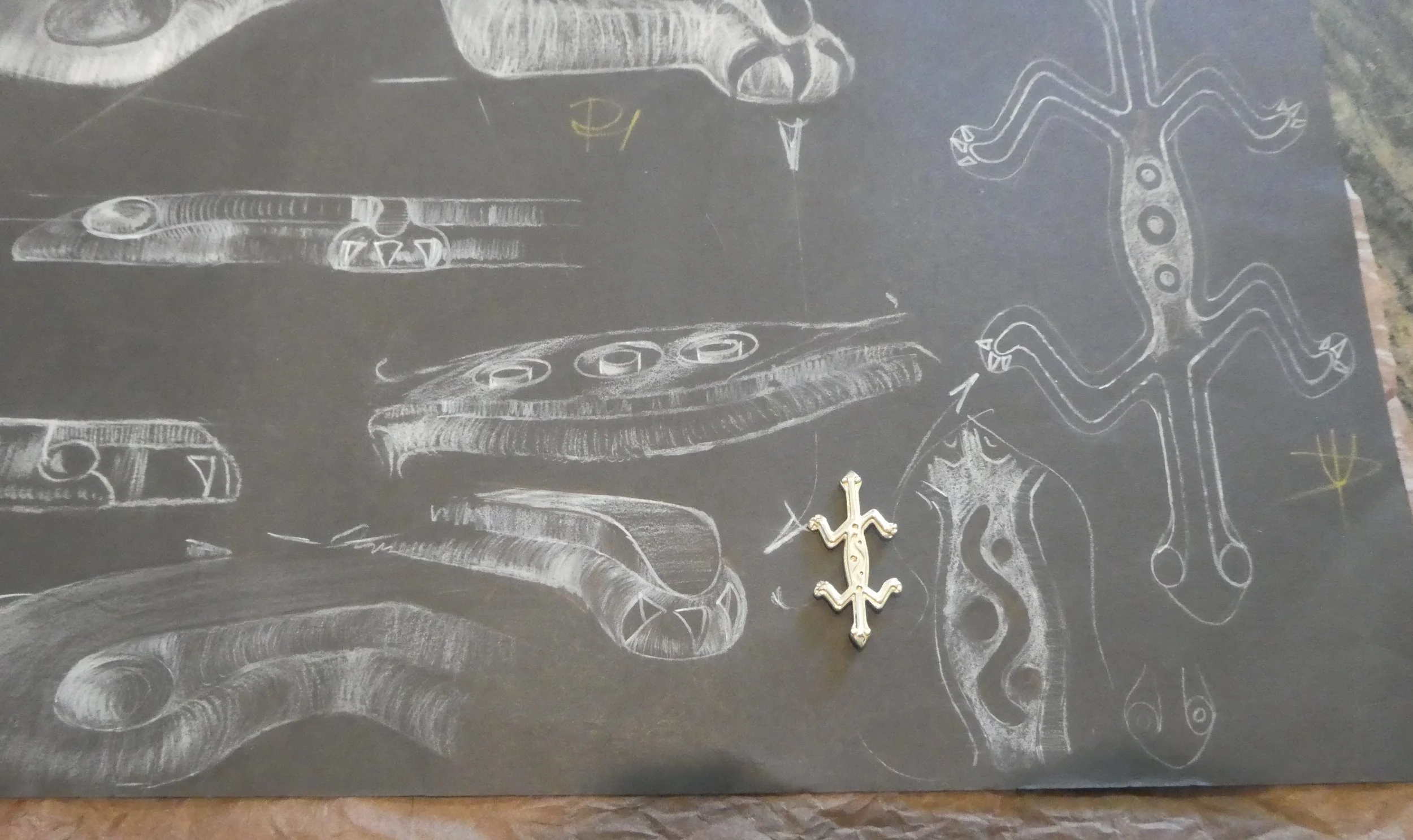 Sketches and diagrams of dinosaur bones and a mounted dinosaur skeleton model, all drawn in white chalk on a blackboard.