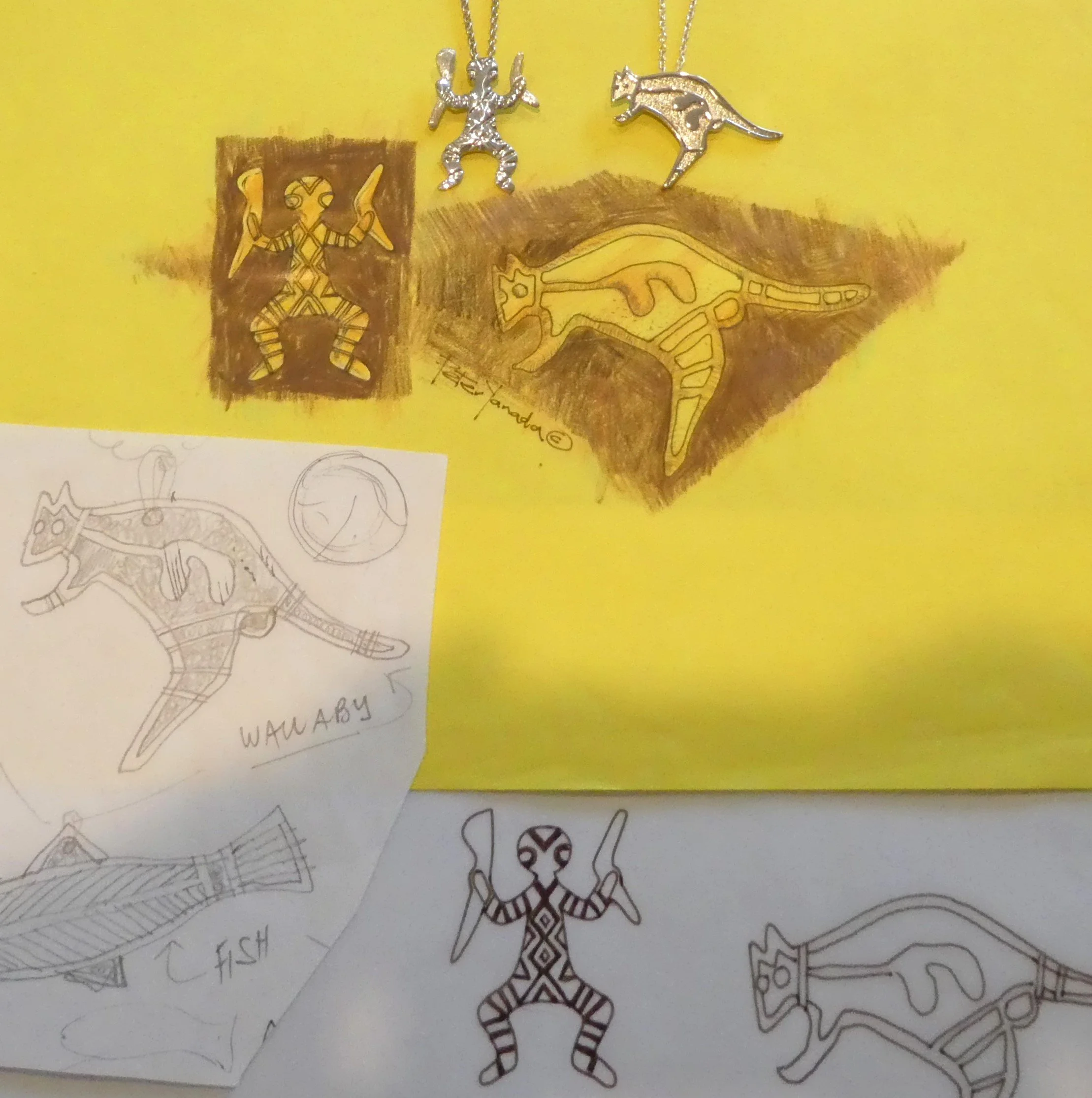 Colorful drawings and jewelry of animals, including cats, a dog, and a fish, on yellow and white paper.