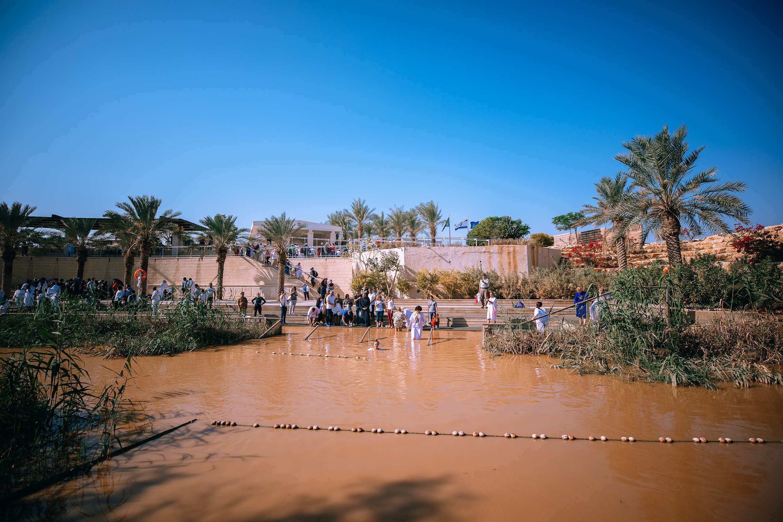 Pilgrims taking a dip in the Jordan River. Israel on the other side.