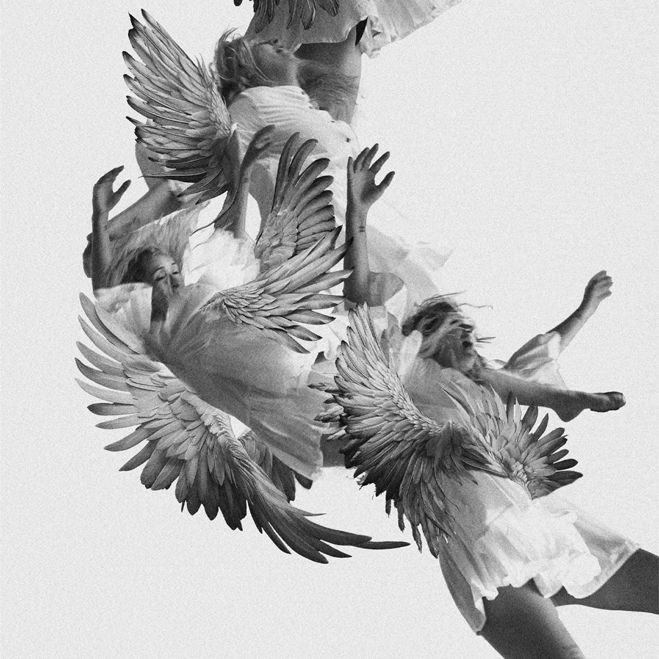 Black and white photo of children with angel wings, dancing and jumping.