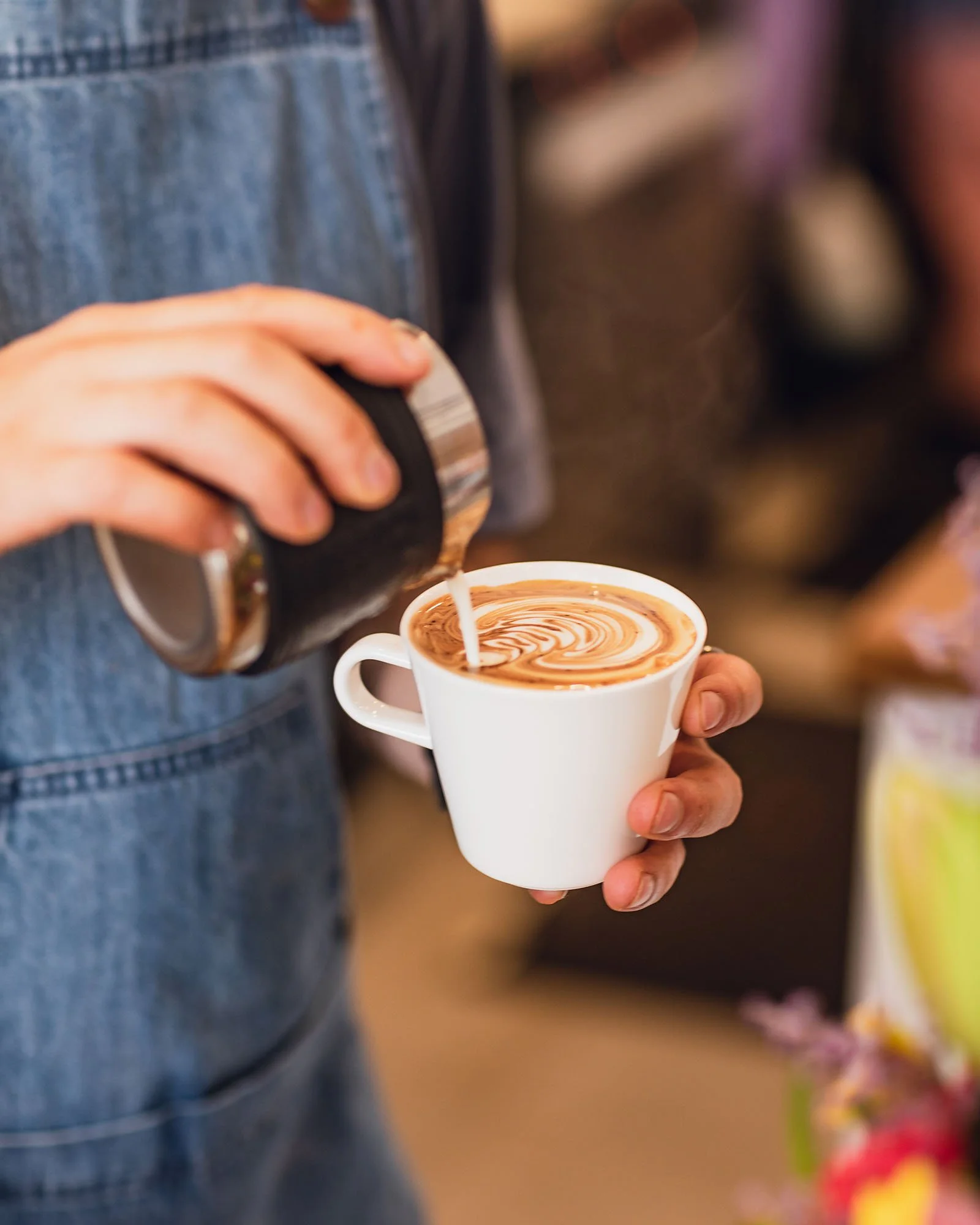 Image Description: An image of a latte being poured into a white cup