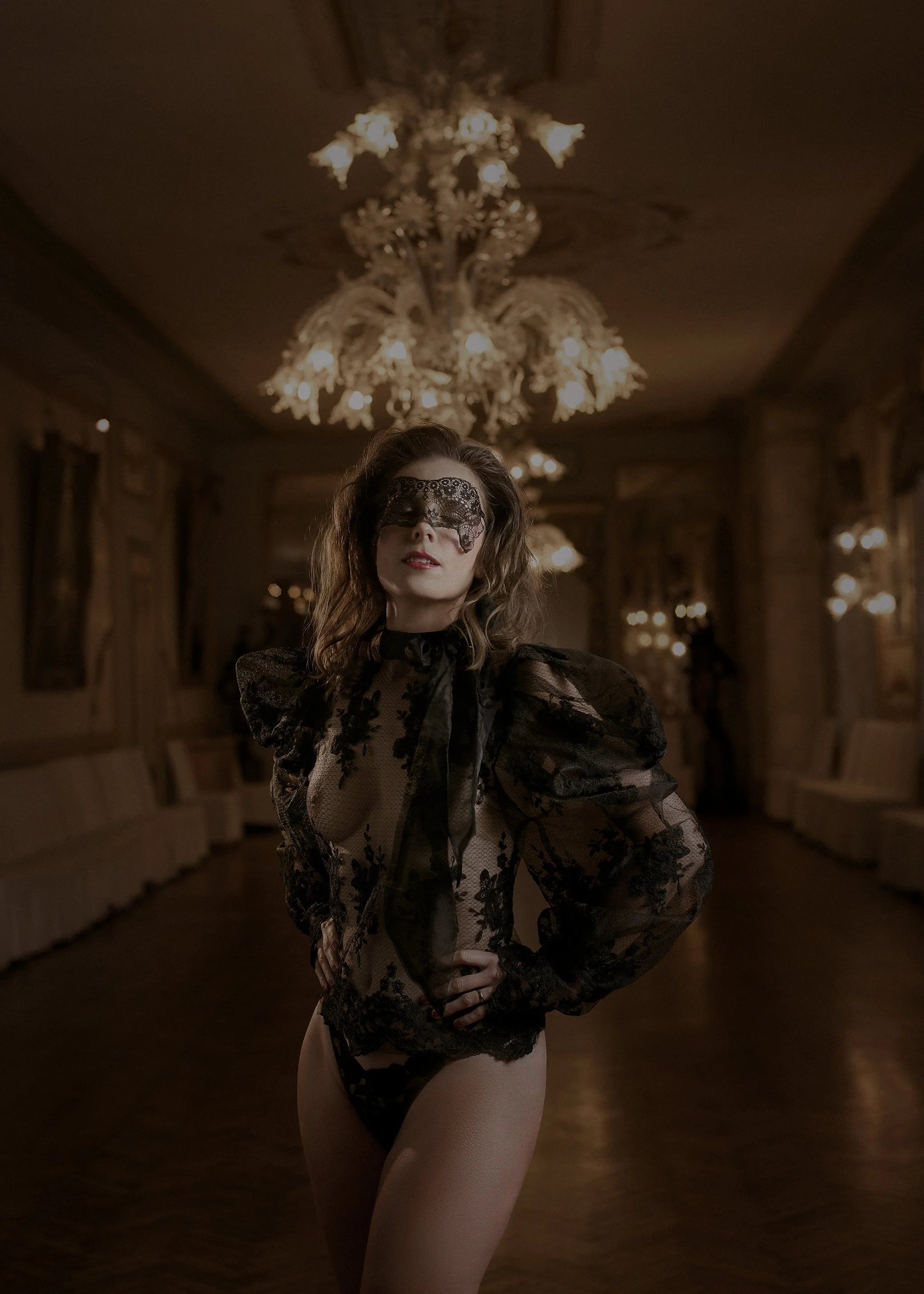 Editorial boudoir portrait in black lace photographed under chandeliers at Castello di Spessa in Italy.
