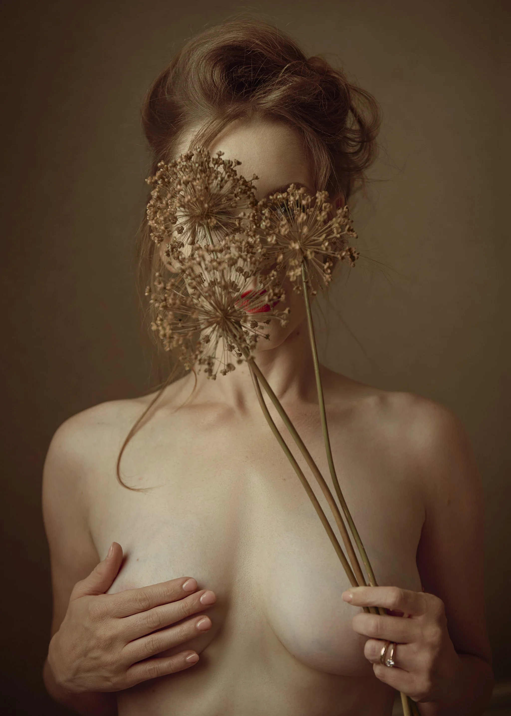 Boudoir portrait of a woman standing with flowers in warm golden light.