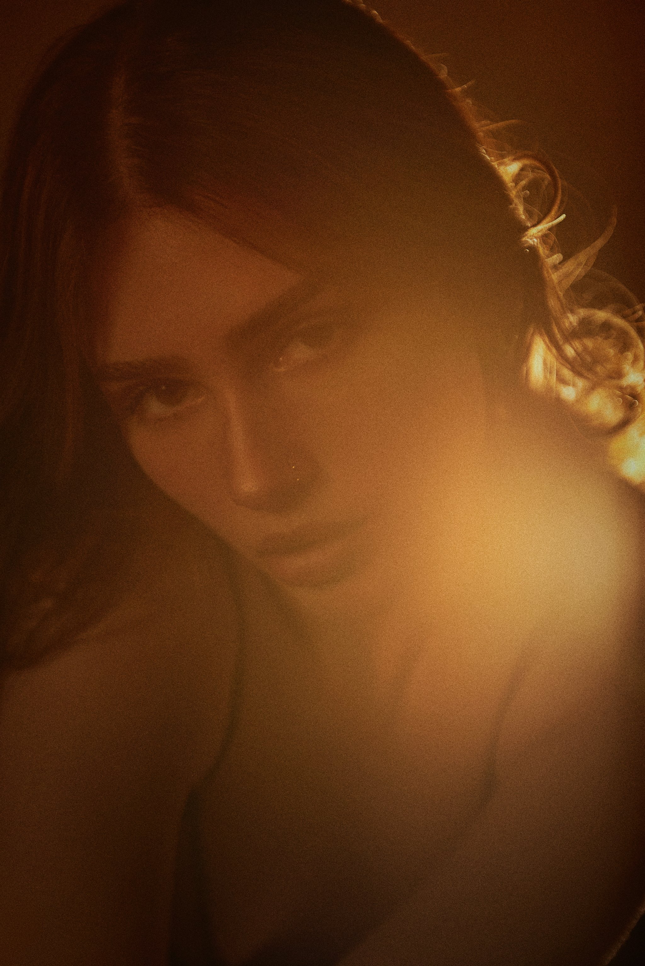 Cinematic boudoir portrait of a woman illuminated by soft, warm golden light.