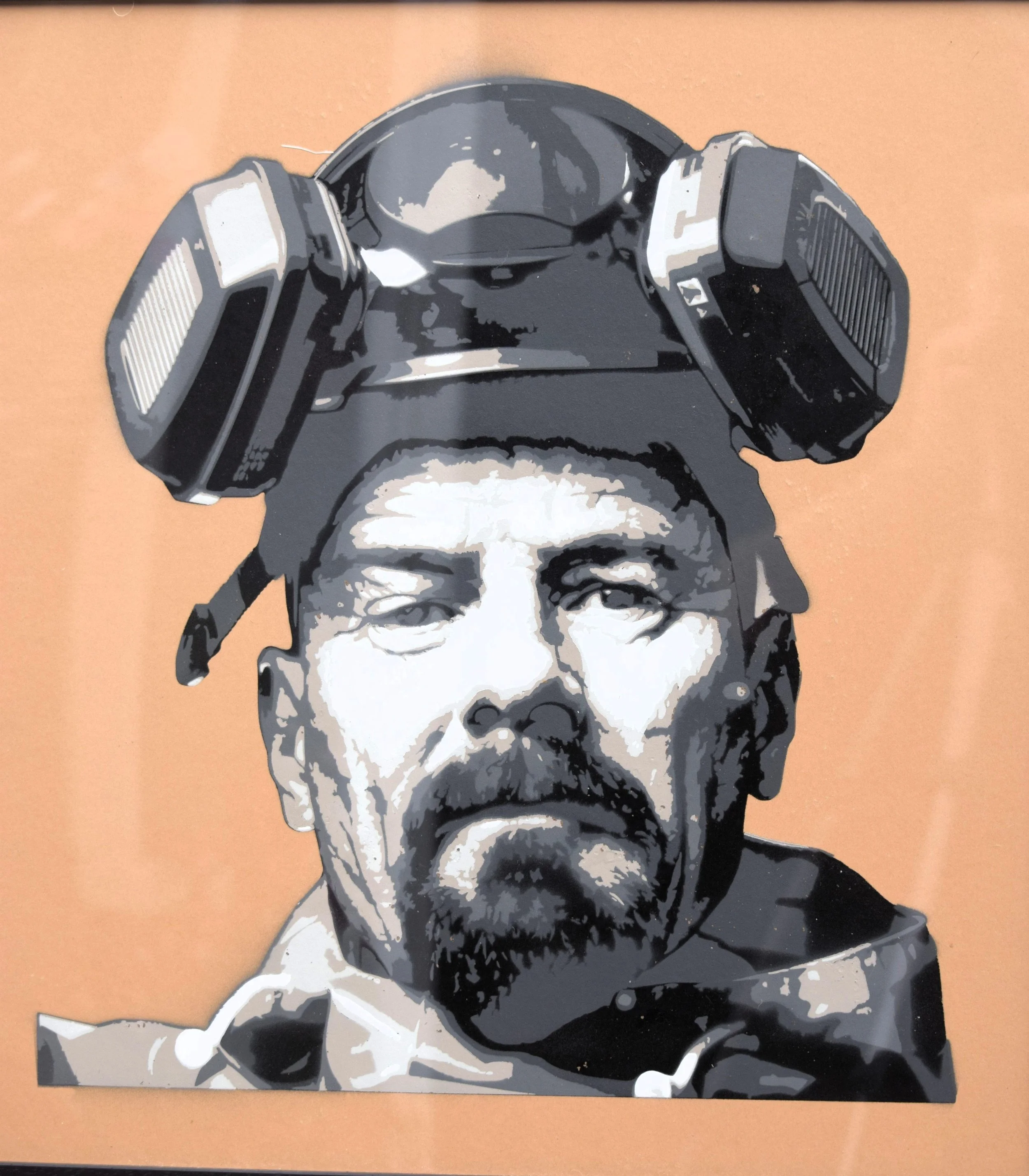 Street art image of a man's face with a beard, wearing a helmet with a VR headset on top.