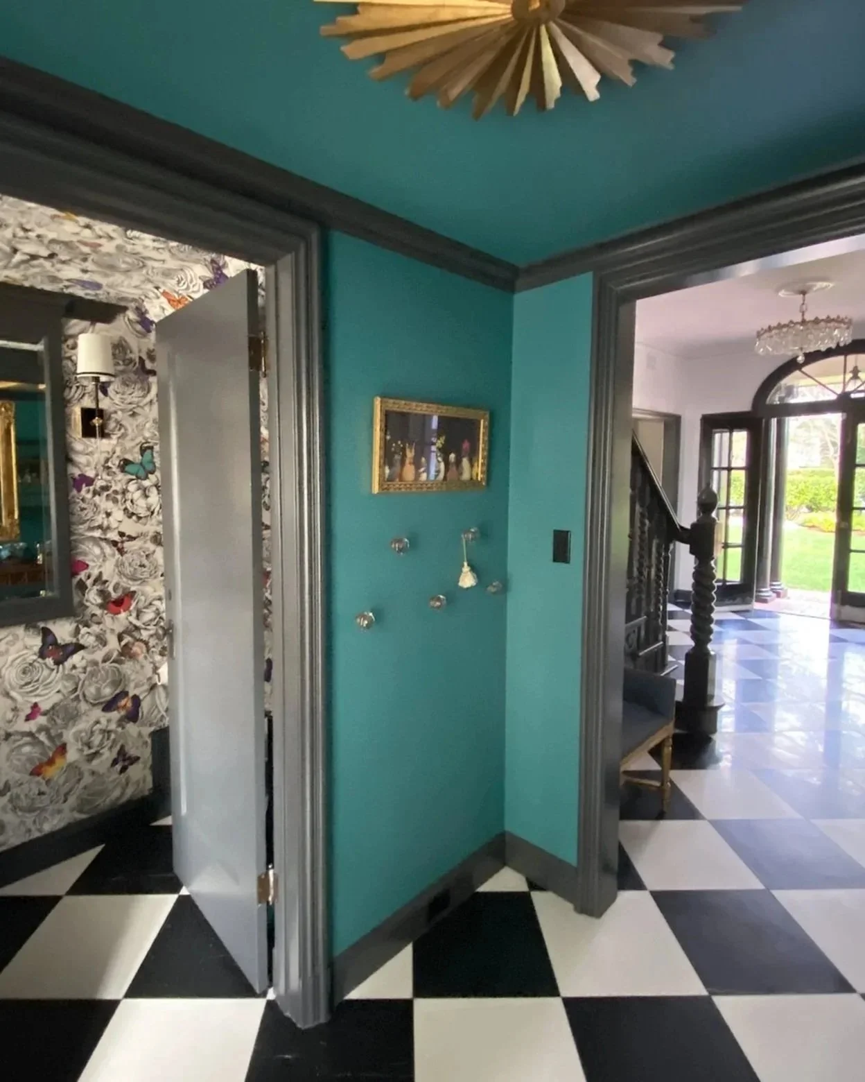 Peak from a hallway into a guest powder room. The Powder room is covered in Osborne & Little Butterfly wall paper.