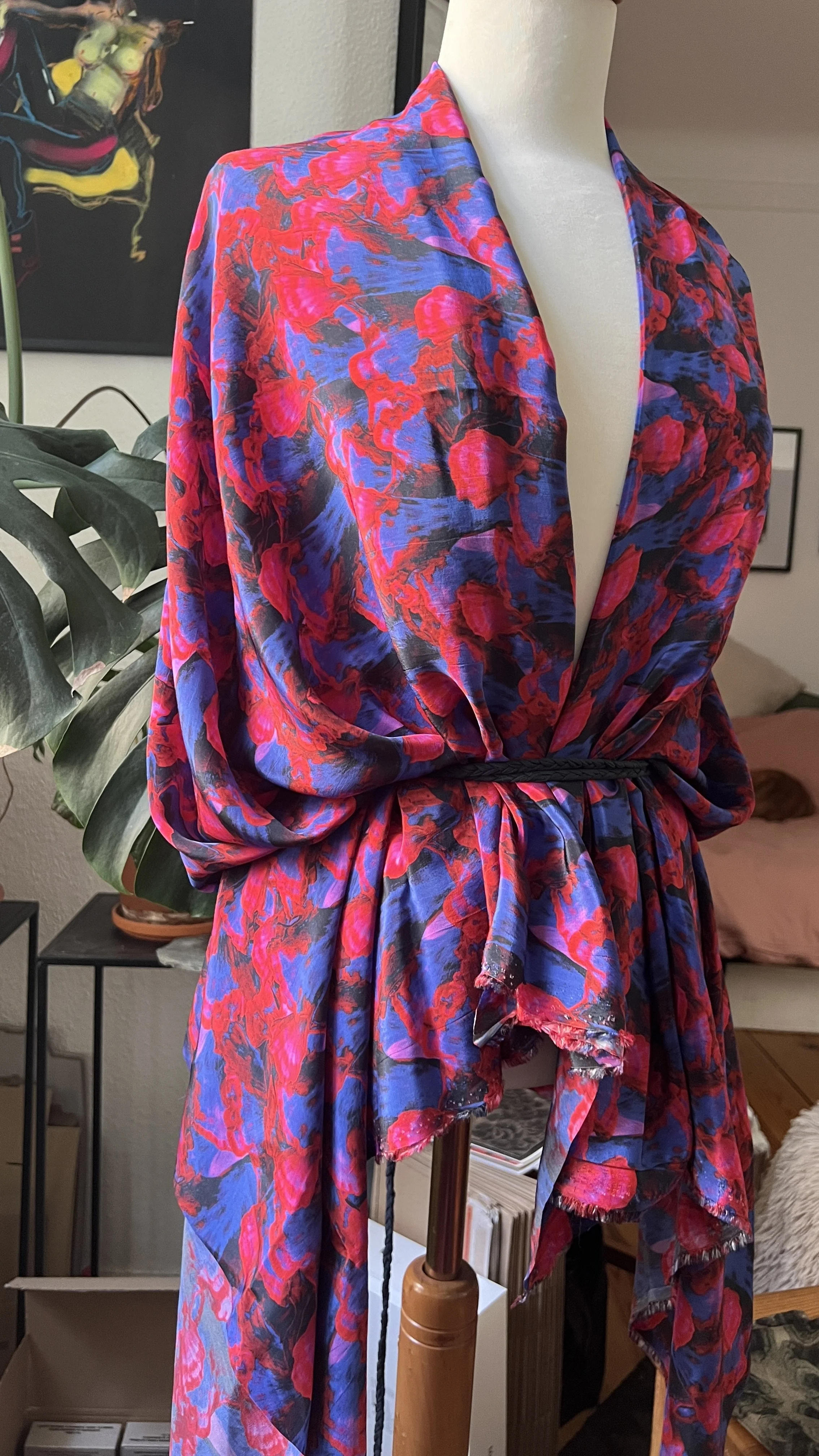 A mannequin dressed in a vibrant, colorful silk wrap dress with abstract floral patterns that are actually mushrooms in shades of red, pink, purple, and blue, tied at the waist with a black cord. Designed by Shhhroooms artist Sharlene Durfey François