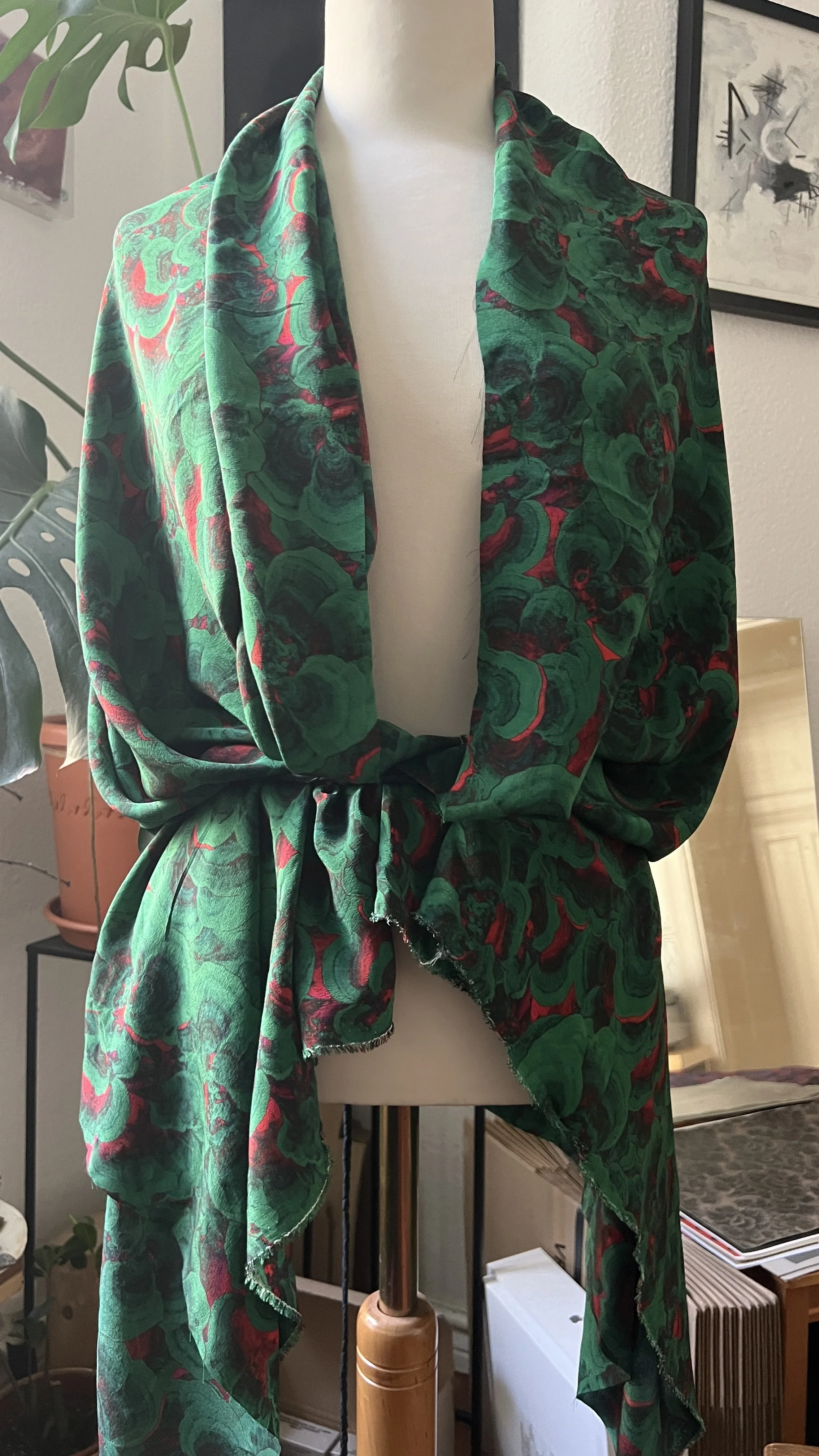 A mannequin dressed in a custom created Turkey Tail print that resembles florals in green, with touches of red and black printed on silk crepe and draped softely over the shoulders and tied around the waist. Shhhroooms custom design.