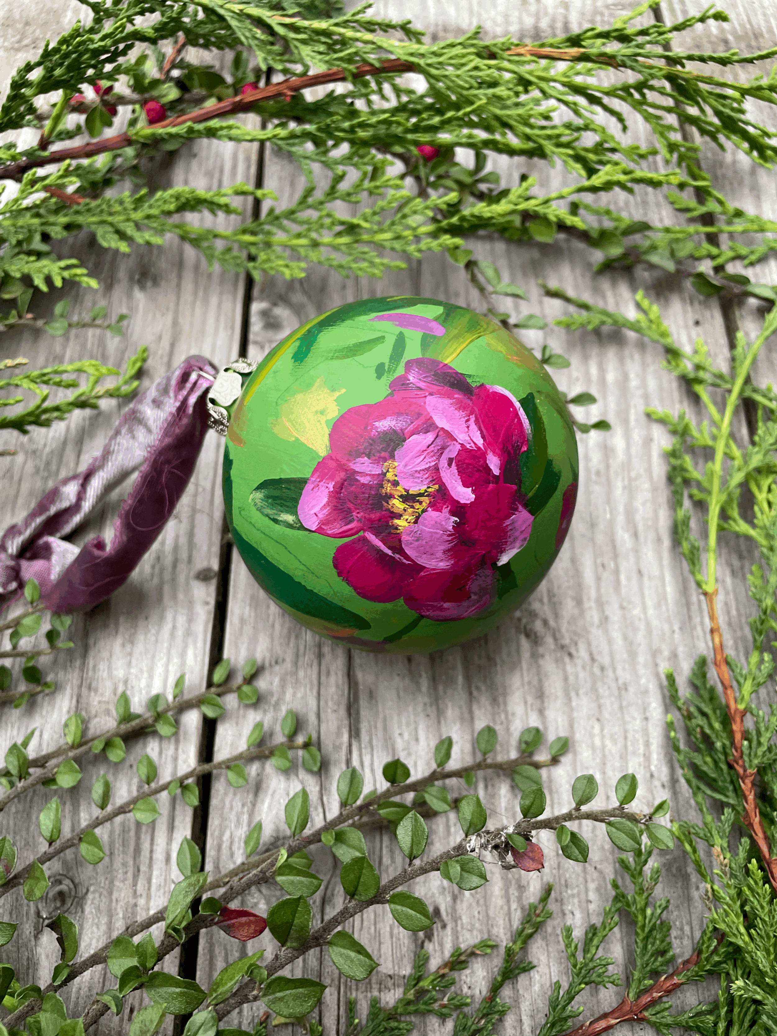 hand painted ceramic floral christmas bauble rich green background with vibrant pink peony flowers