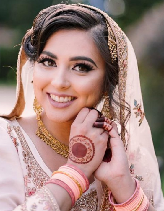 Smiling woman in traditional attire with henna on hand and colorful bangles