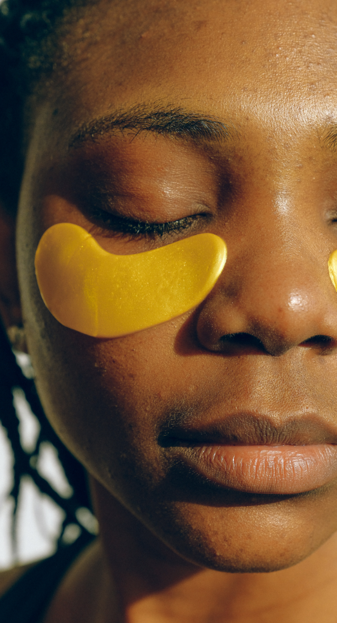 Close-up of a person wearing golden under-eye patches, eyes closed.