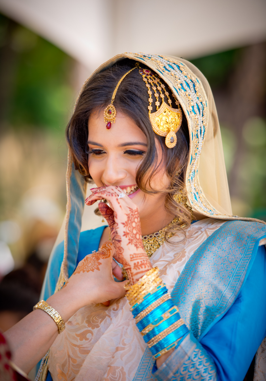 Smiling woman in traditional attire with henna and gold jewelry