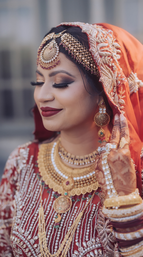 Bride in traditional South Asian wedding attire with intricate jewelry and henna tattoos.