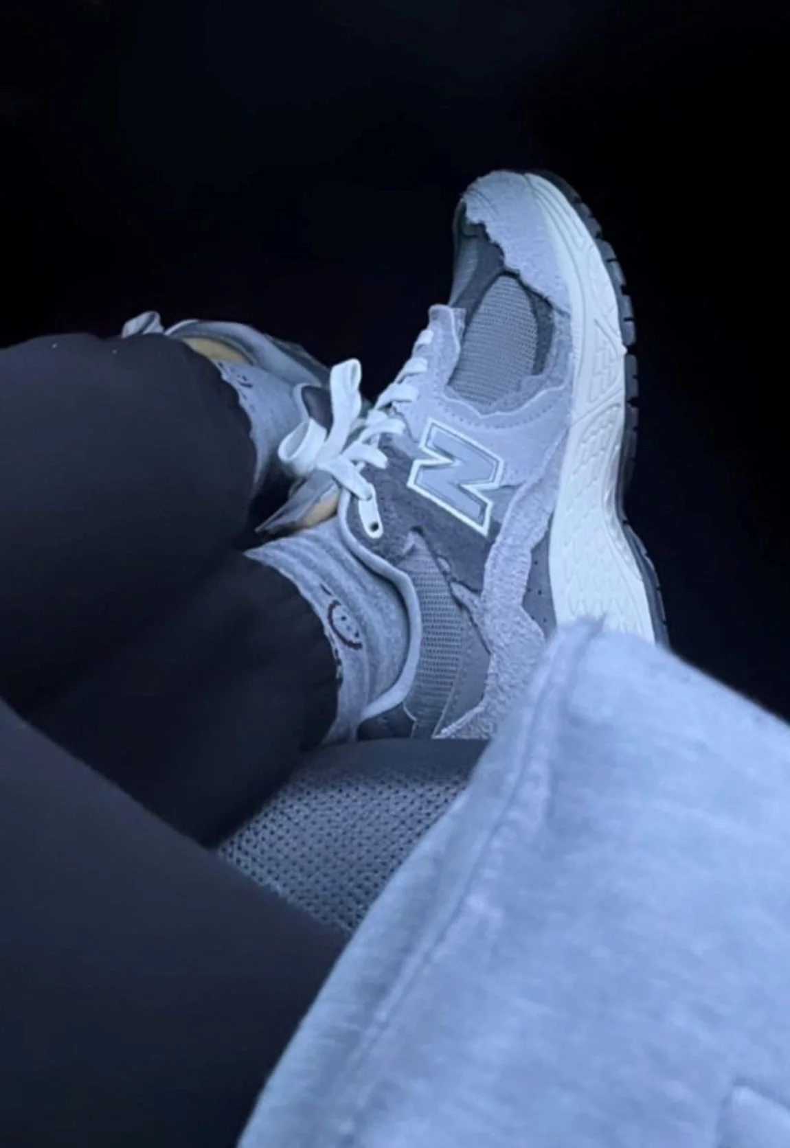 A person's feet in gray sneakers