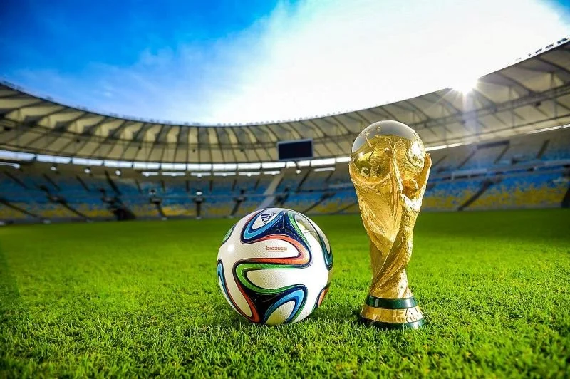 Soccer ball and World Cup trophy in stadium