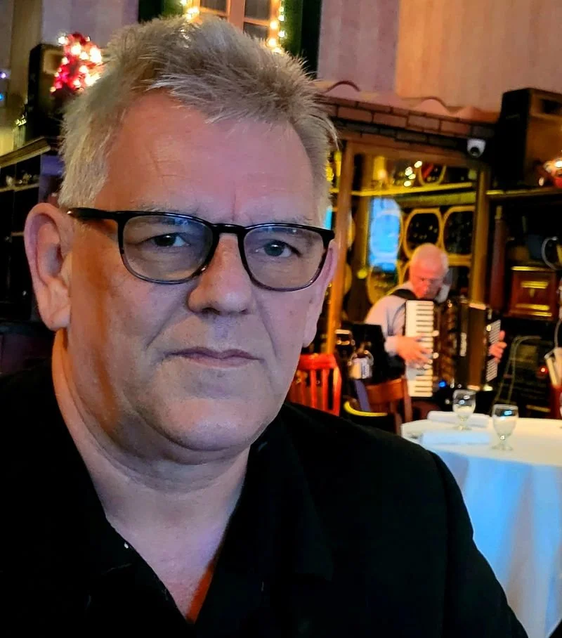Documentary filmmaker Nigel Bellis in black shirt at a restaurant