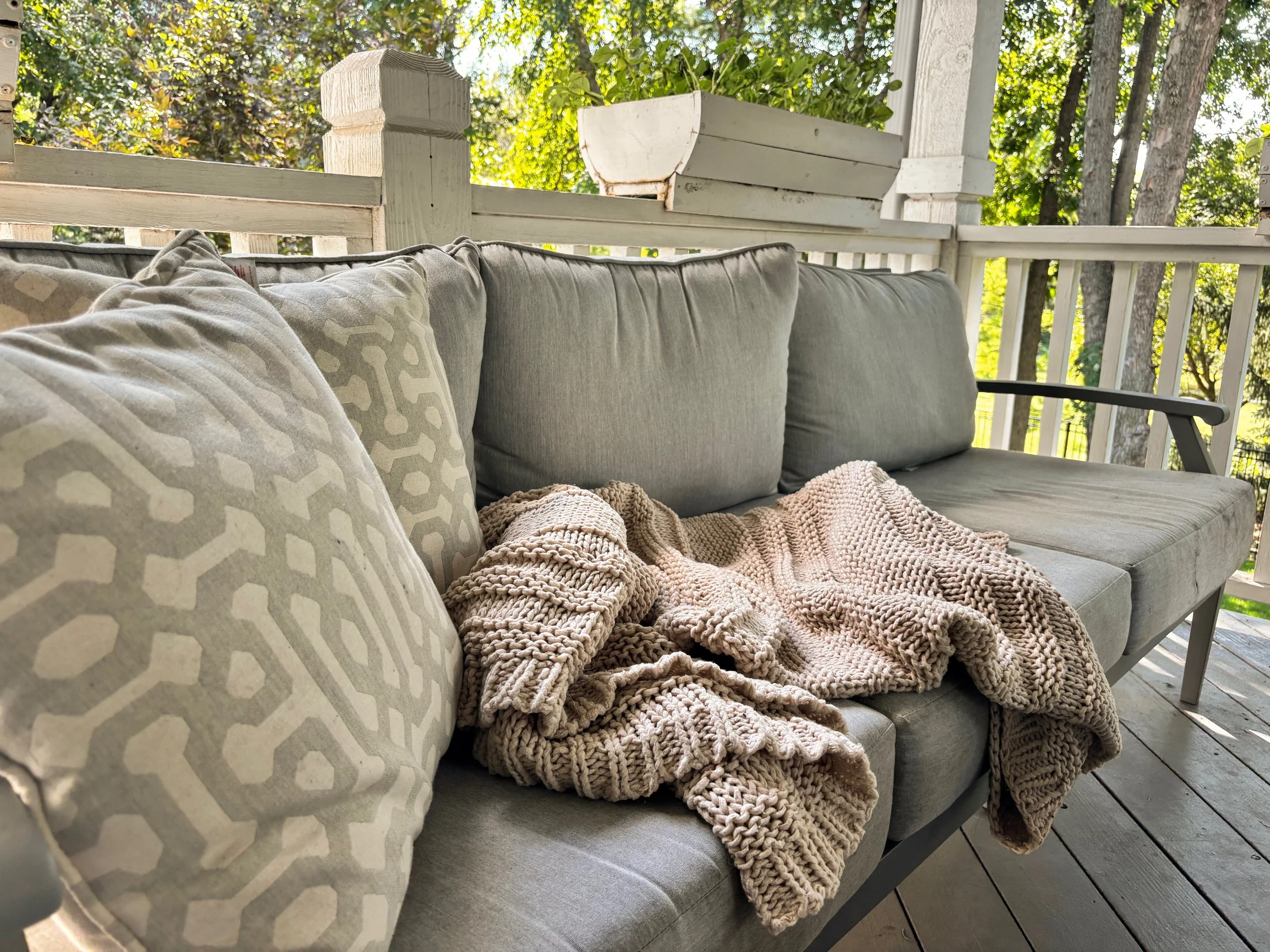 Grey couch with pillows and a tan blanket