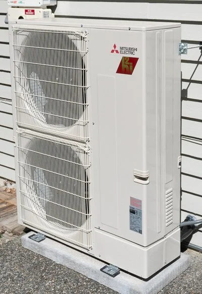 The outdoor unit of a heat pump is shown outside of a house