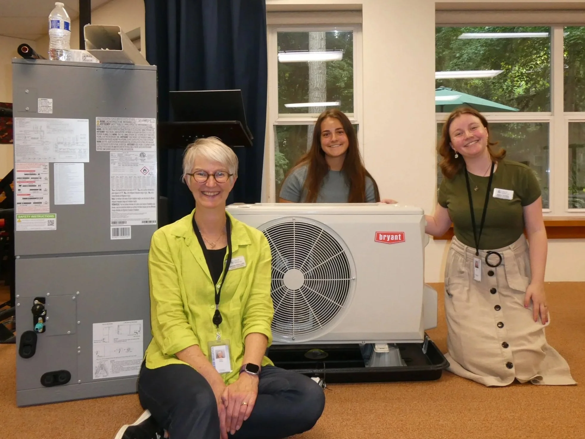 Energy Smart Eastside staff sit next to a demonstration heat pump during a community workshop
