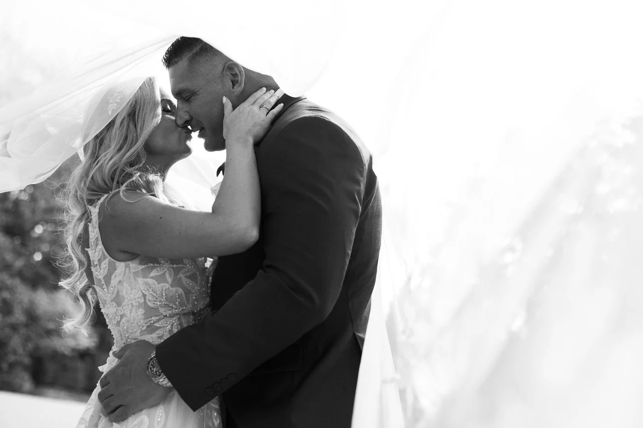 Black and white photo of a bride and groom sharing a kiss under her veil at a New Jersey wedding