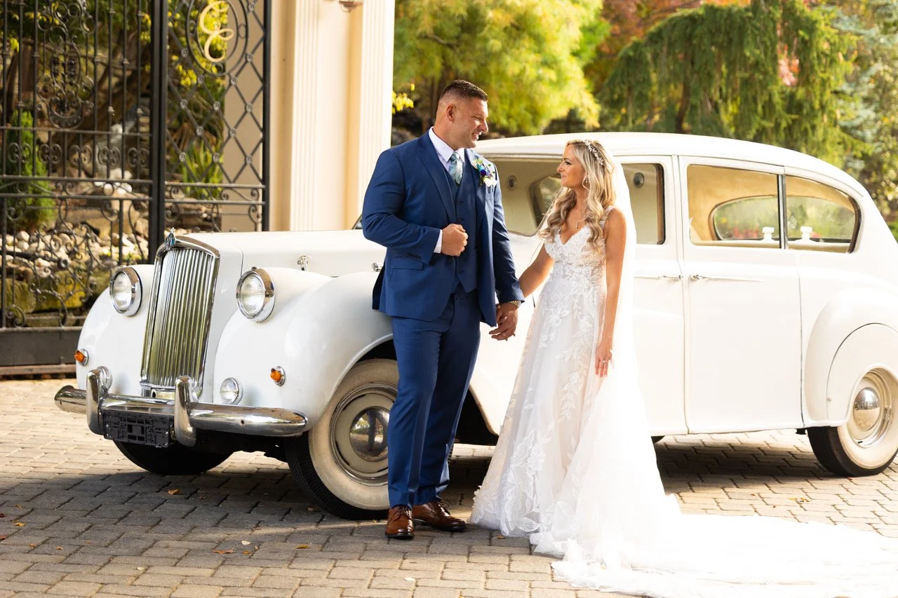 Bride and groom walking beside a vintage white car on their New Jersey wedding day