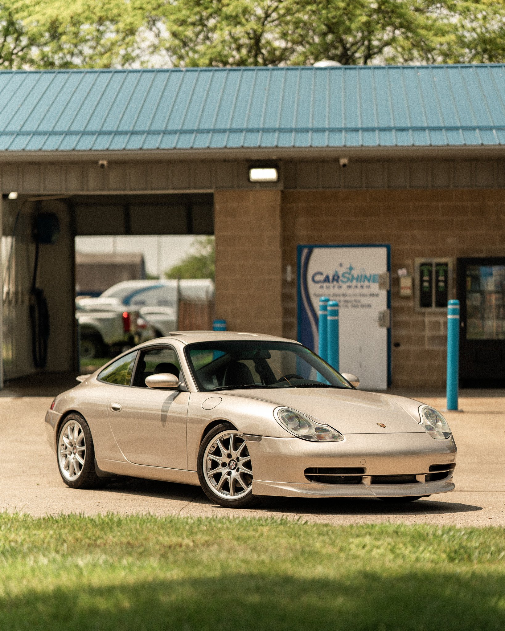 Silver sports car parked in front of a car wash with a blue roof.