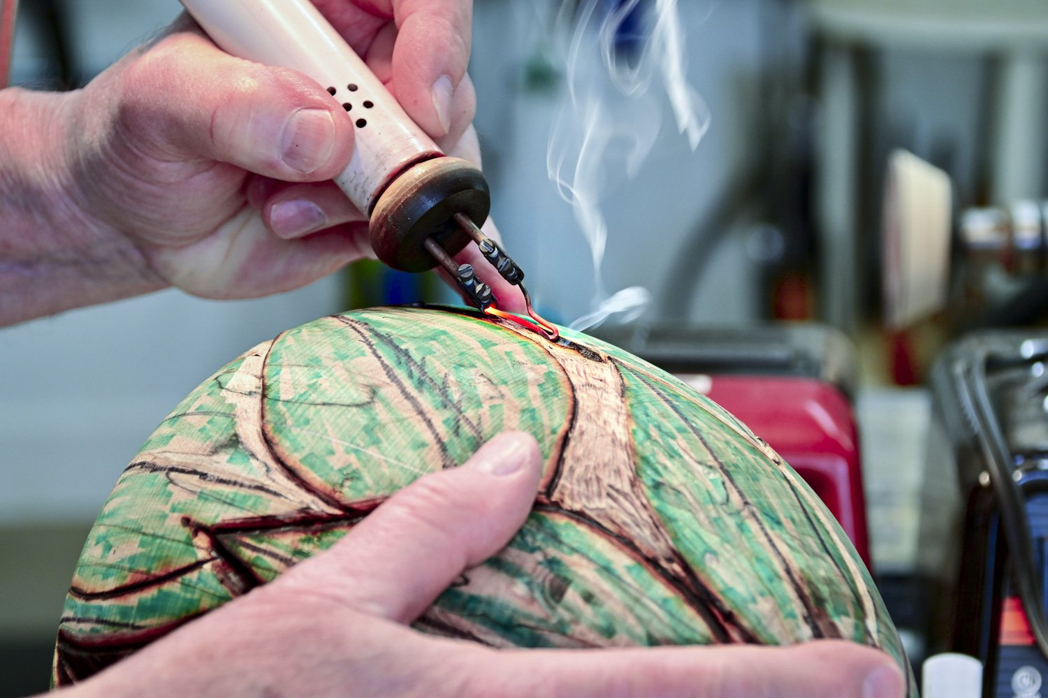 Steve Miller carving a leaf patterned texture into the surface of a turned wood bowl with pyrographic tool.