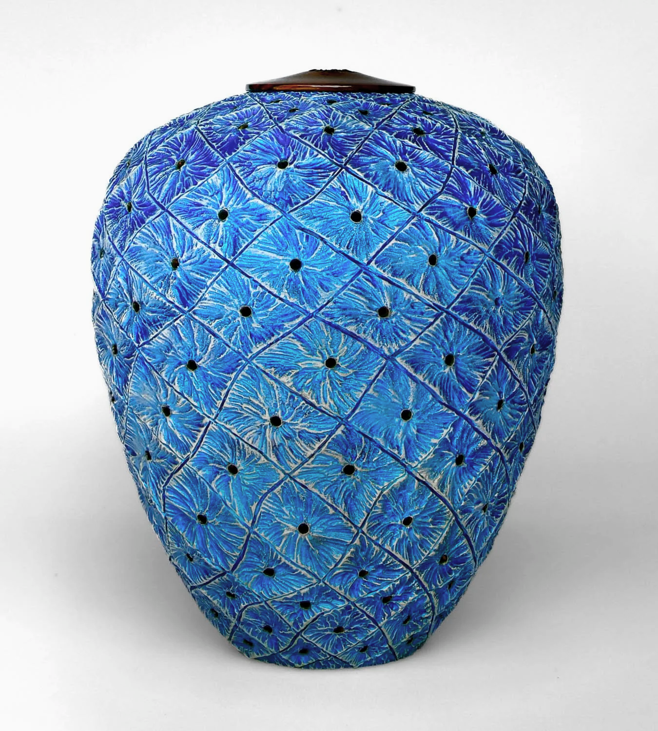 A blue and black turned and carved one-of-a-kind wood vase with a geometric coral inspired pattern and small black dots.