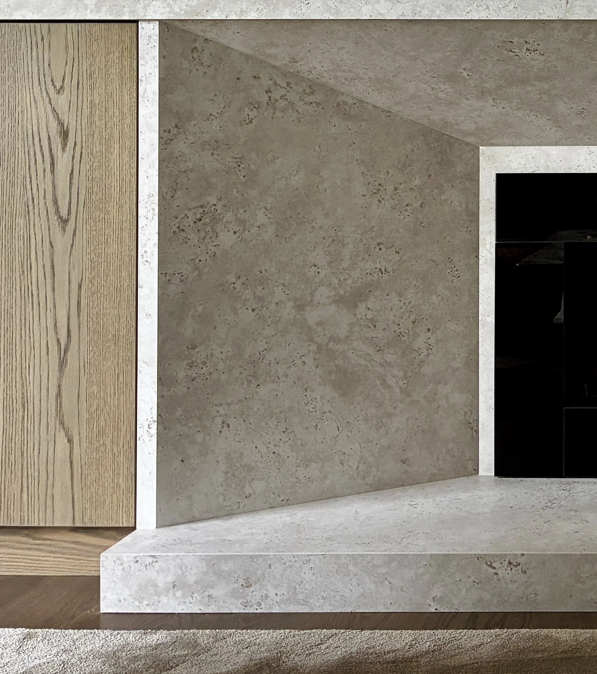 Close-up of a modern fireplace with a concrete surround and a wooden wall on the left side.