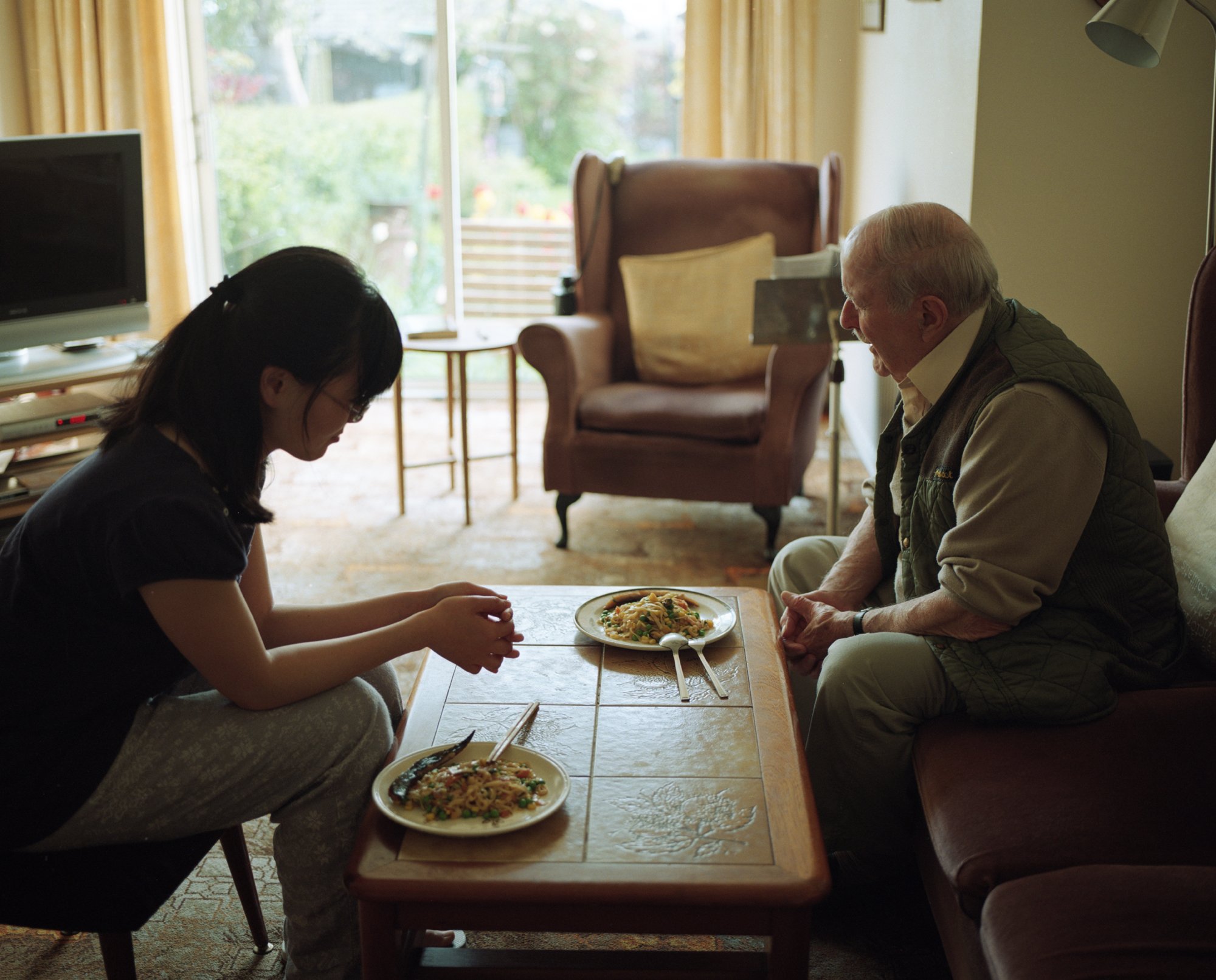  Qingqing, a student from Tianjin in China with her homestay host Uncle Douglas as they say grace before dinner, Sheffield.  