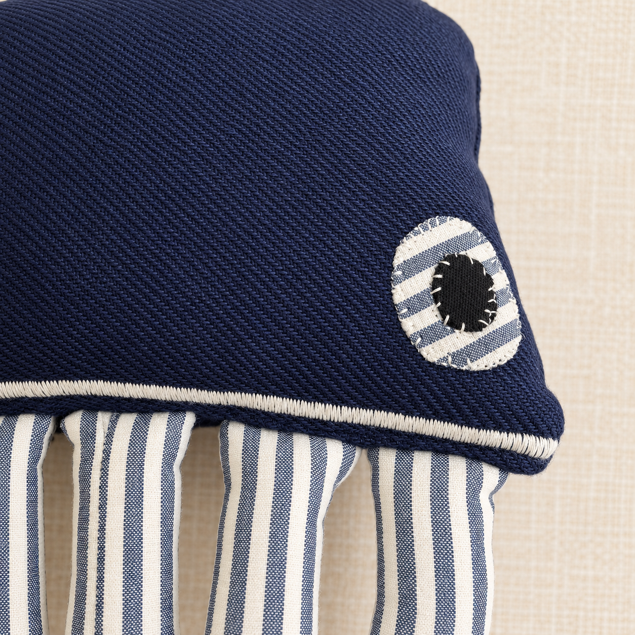 Close-up of natural cotton fabric, stitched eyes and handmade details on a navy blue artisan octopus.
