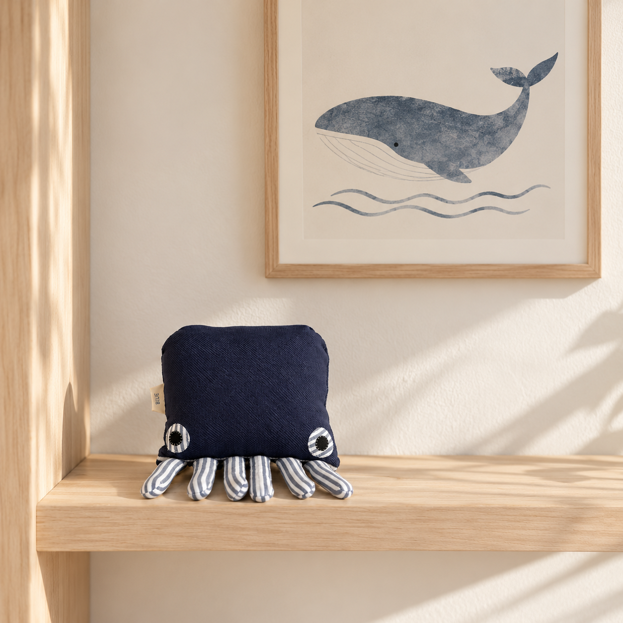 Handmade navy blue octopus textile sculpture displayed on a timber shelf in a minimalist nursery.