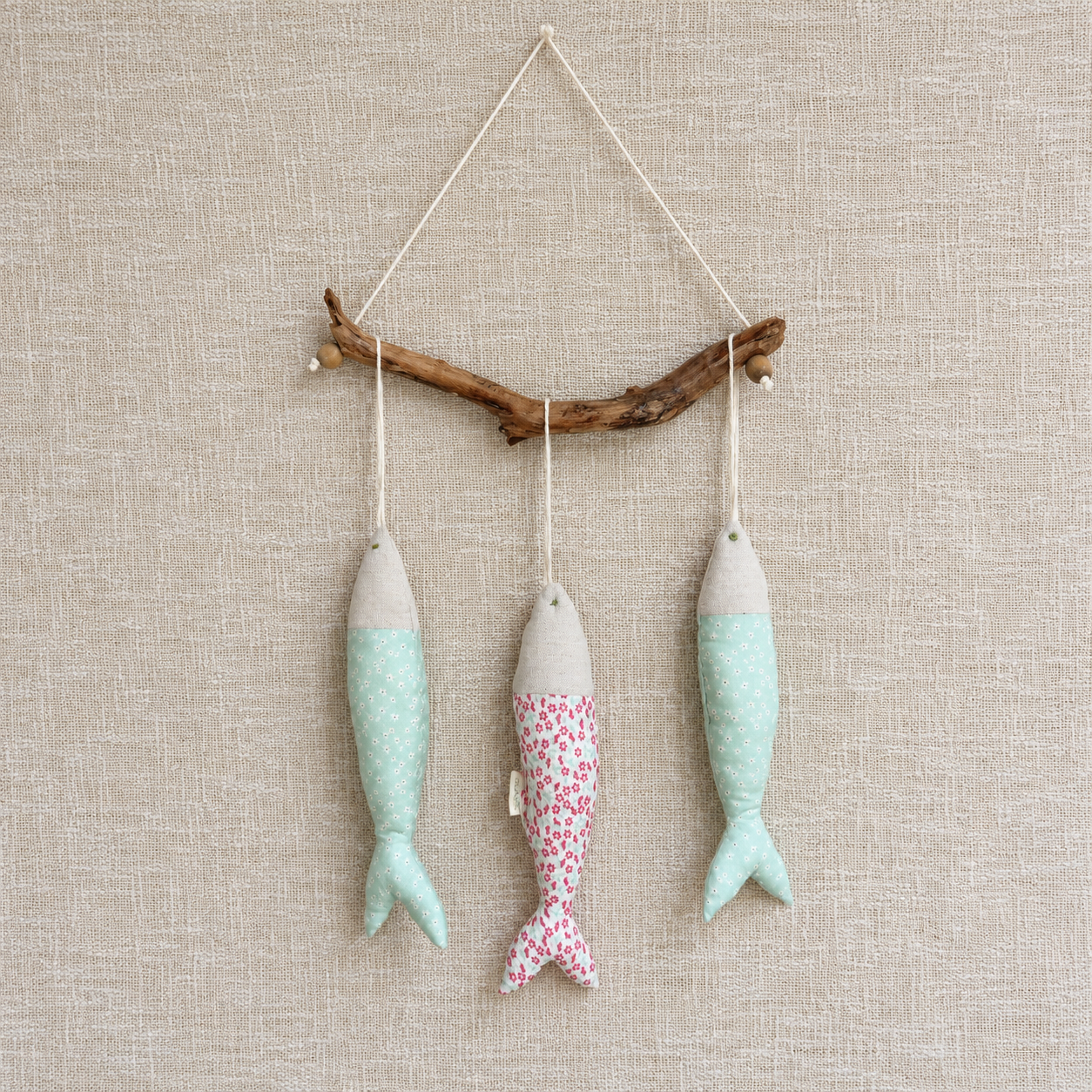 Handmade cotton fish mobile suspended from natural driftwood, designed as decorative textile art for homes and nurseries.