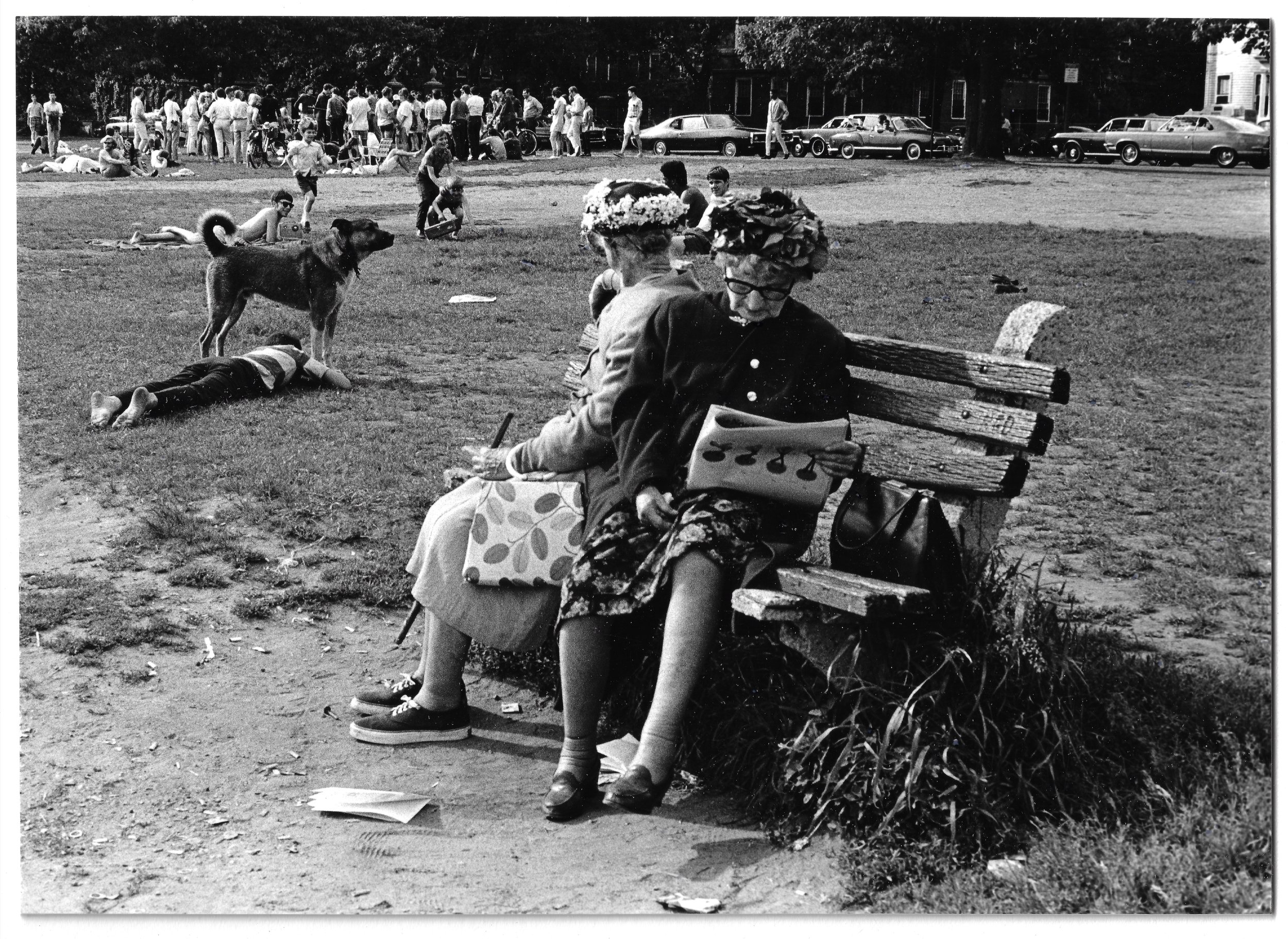 On the bankcs of the Charles, two women in flowered hats. 