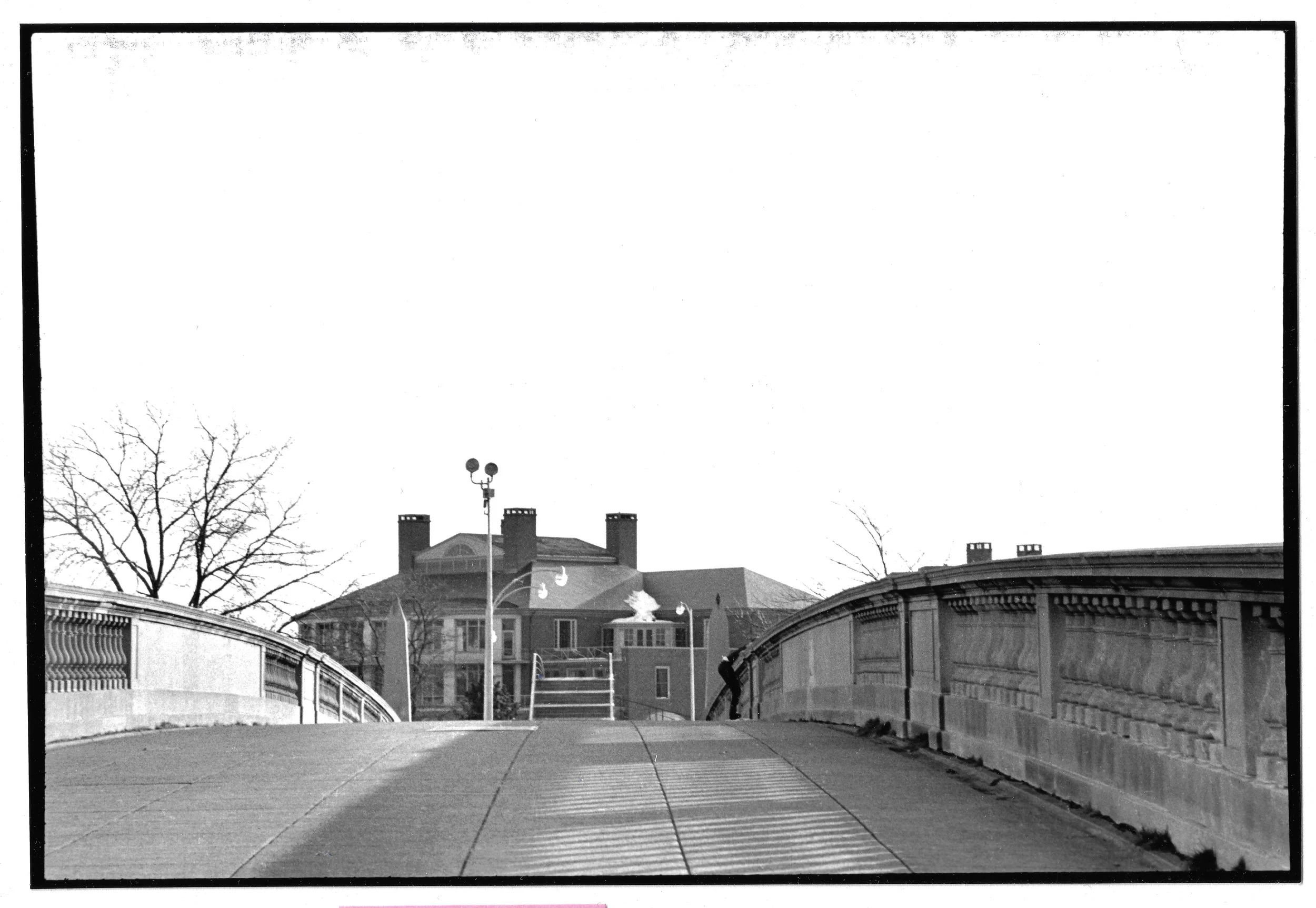 Bridge over the Charles, with a small figure leaning over, to the back on the right side.