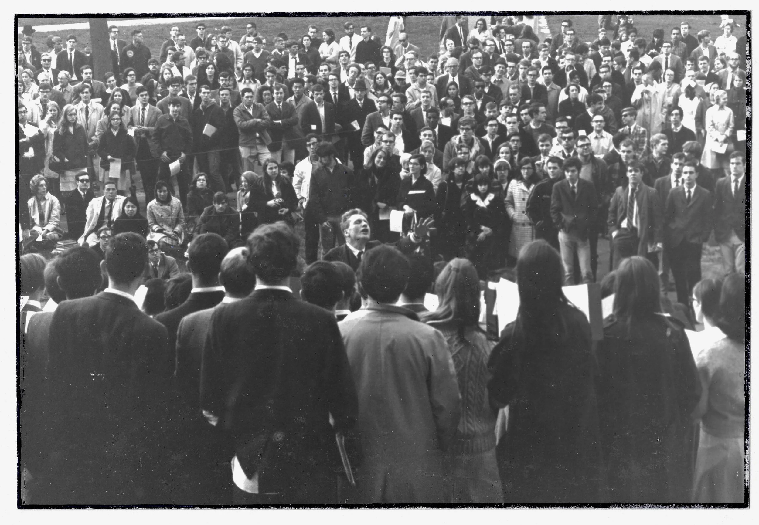 Choral musuc professor leads a performance on the steps of Widener Library to a hug appreciative crowd.