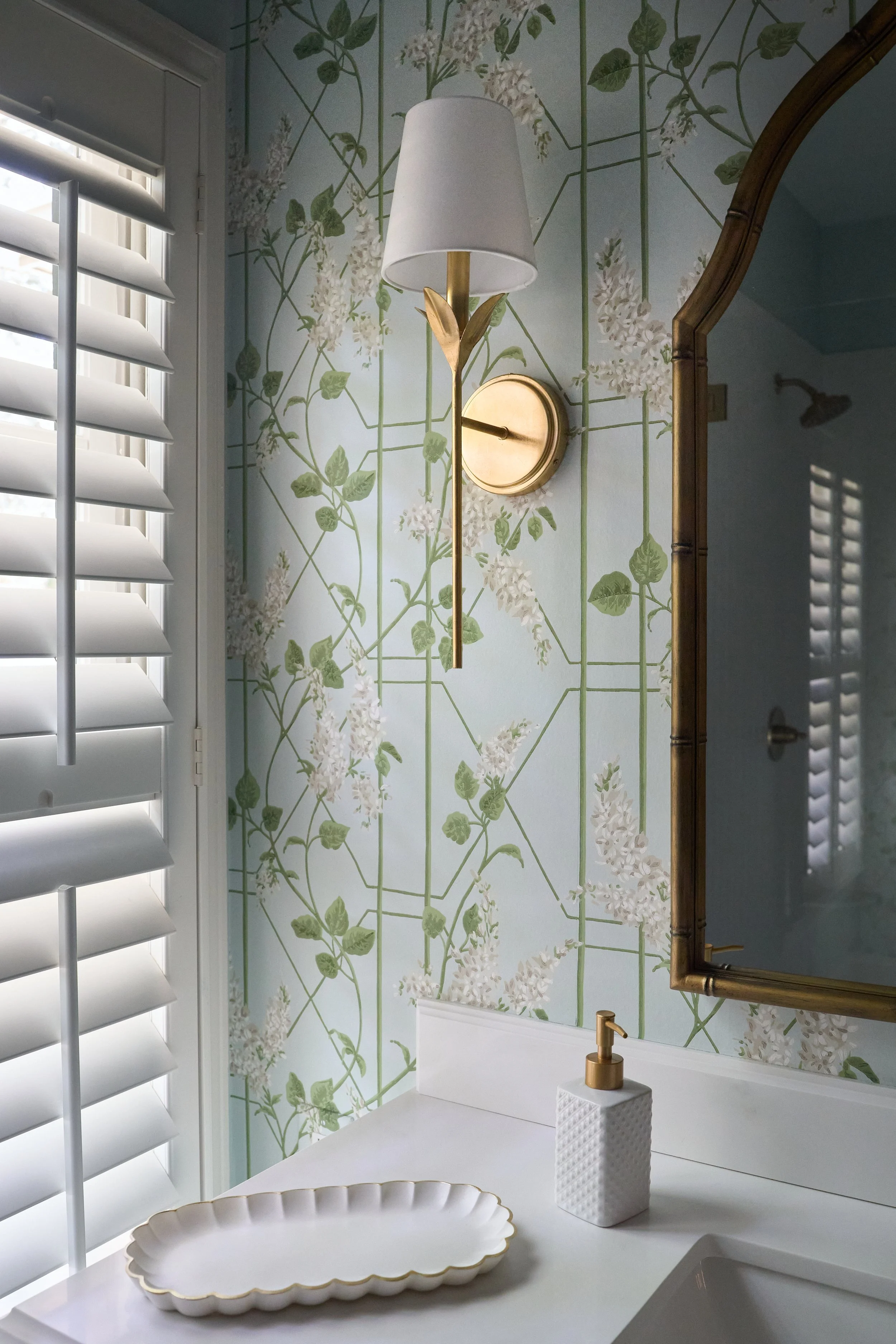 photo of a vanity and vanity light in a bathroom with floral wallpaper.
