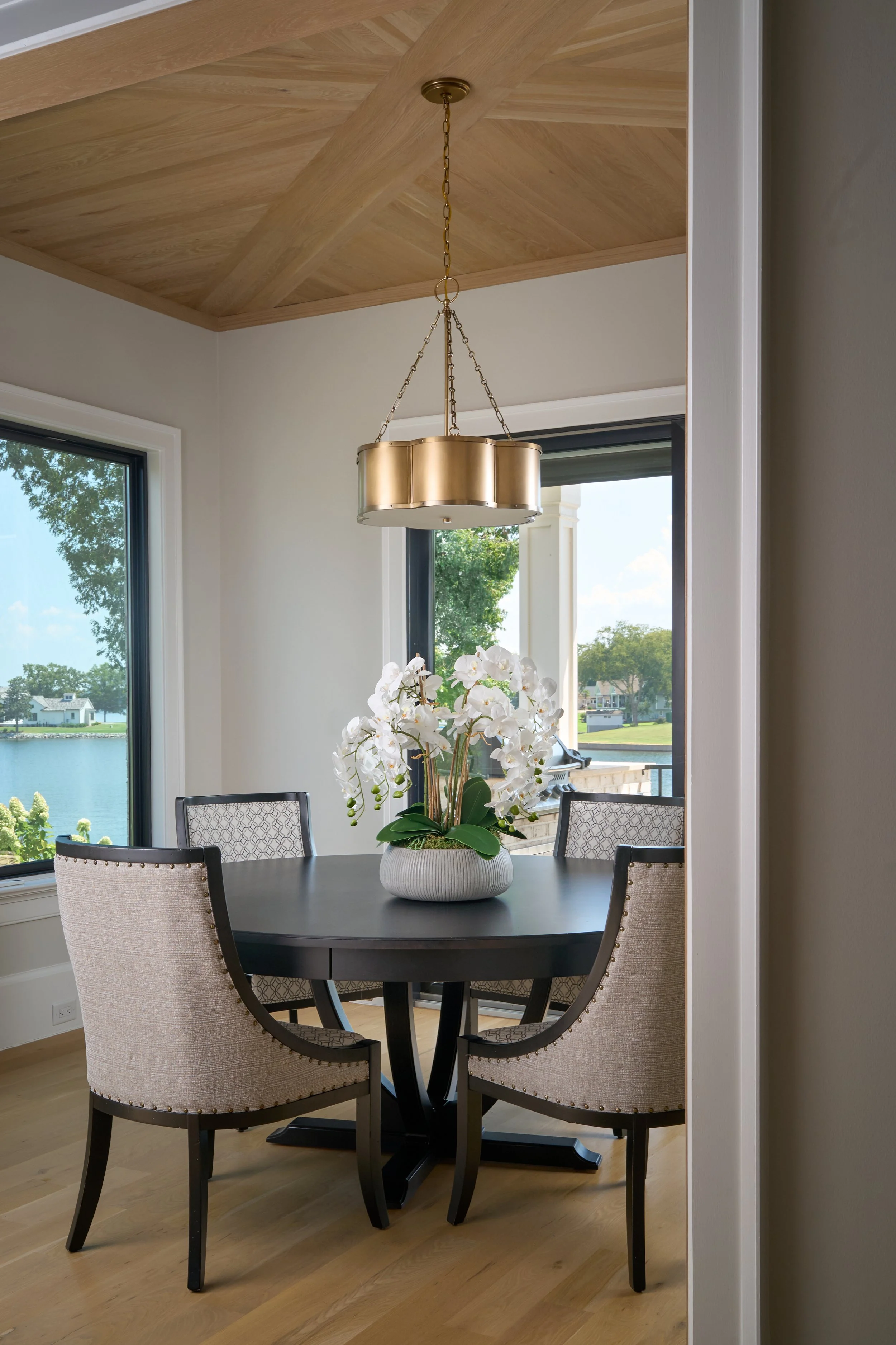 a dining room with wood paneled ceiling and a lake view