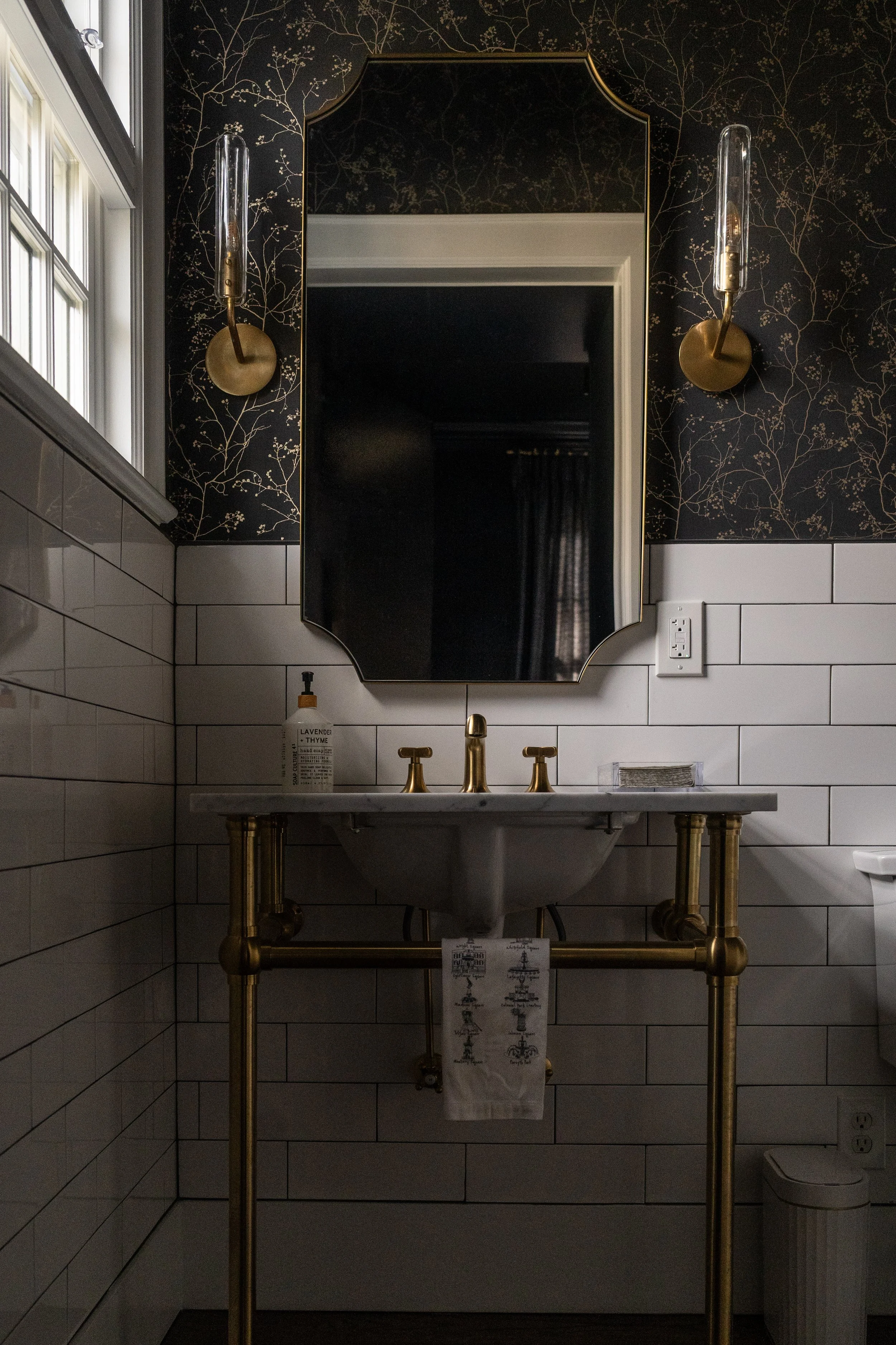 sink, mirror, and lighting in a moody powder bathroom with dark gray wallpaper