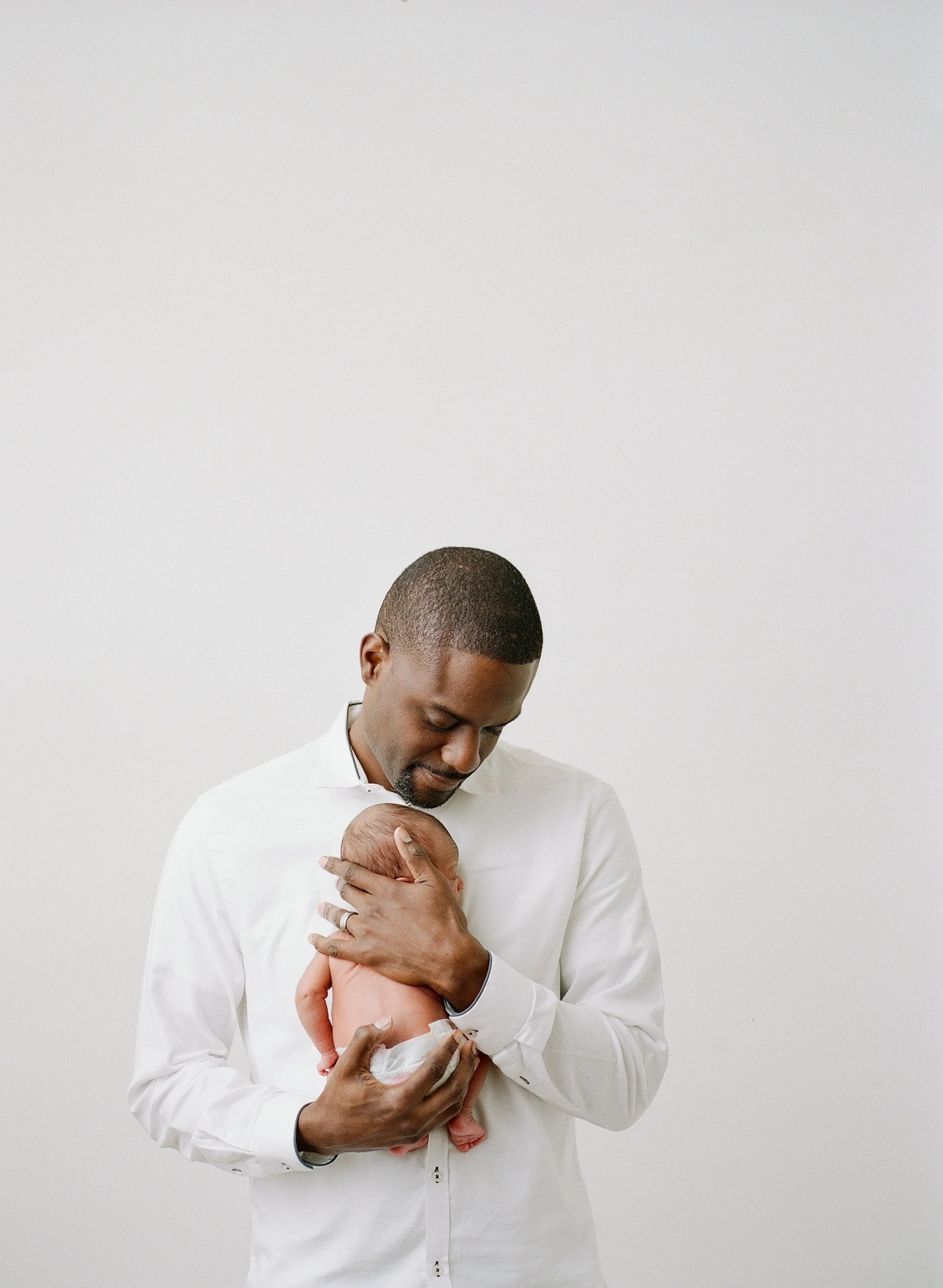 Father holding newborn baby to his chest. Flash photography.