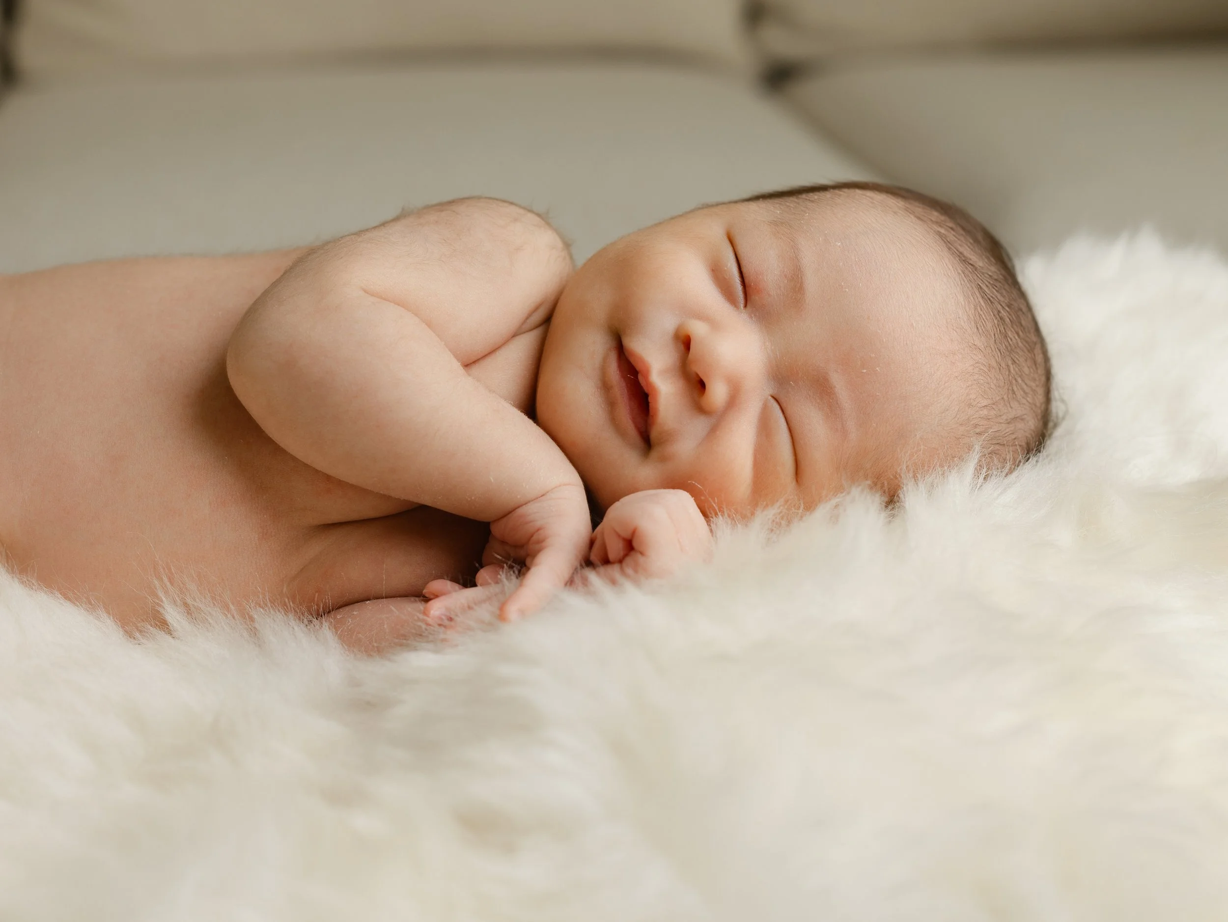 Newborn baby smiling in their sleep, lifestyle photography, off-camera flash