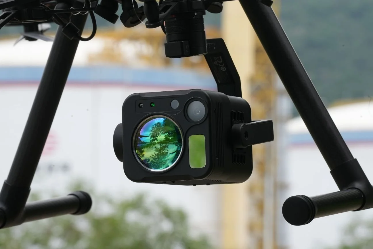 A closed-up side view of a drone equipped with a Purway UAV TDLAS methane detector flying over a refinery in an industrial park