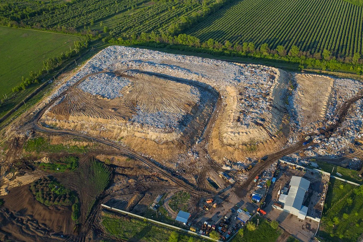 Aerial perspective of a landfill construction site, featuring machinery and various construction materials scattered across the area