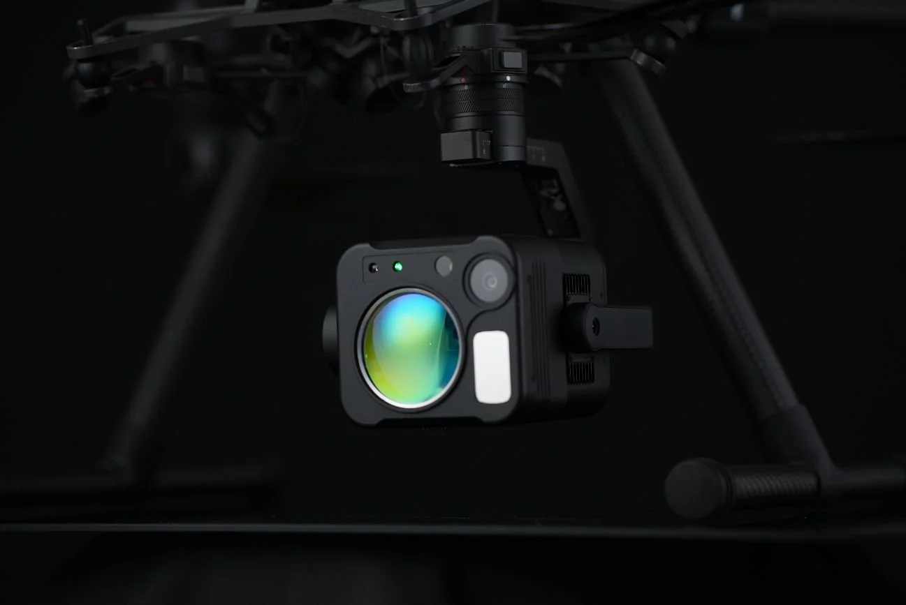 A drone with a green-lit camera mounted, showcasing a methane detection payload against a dark backdrop