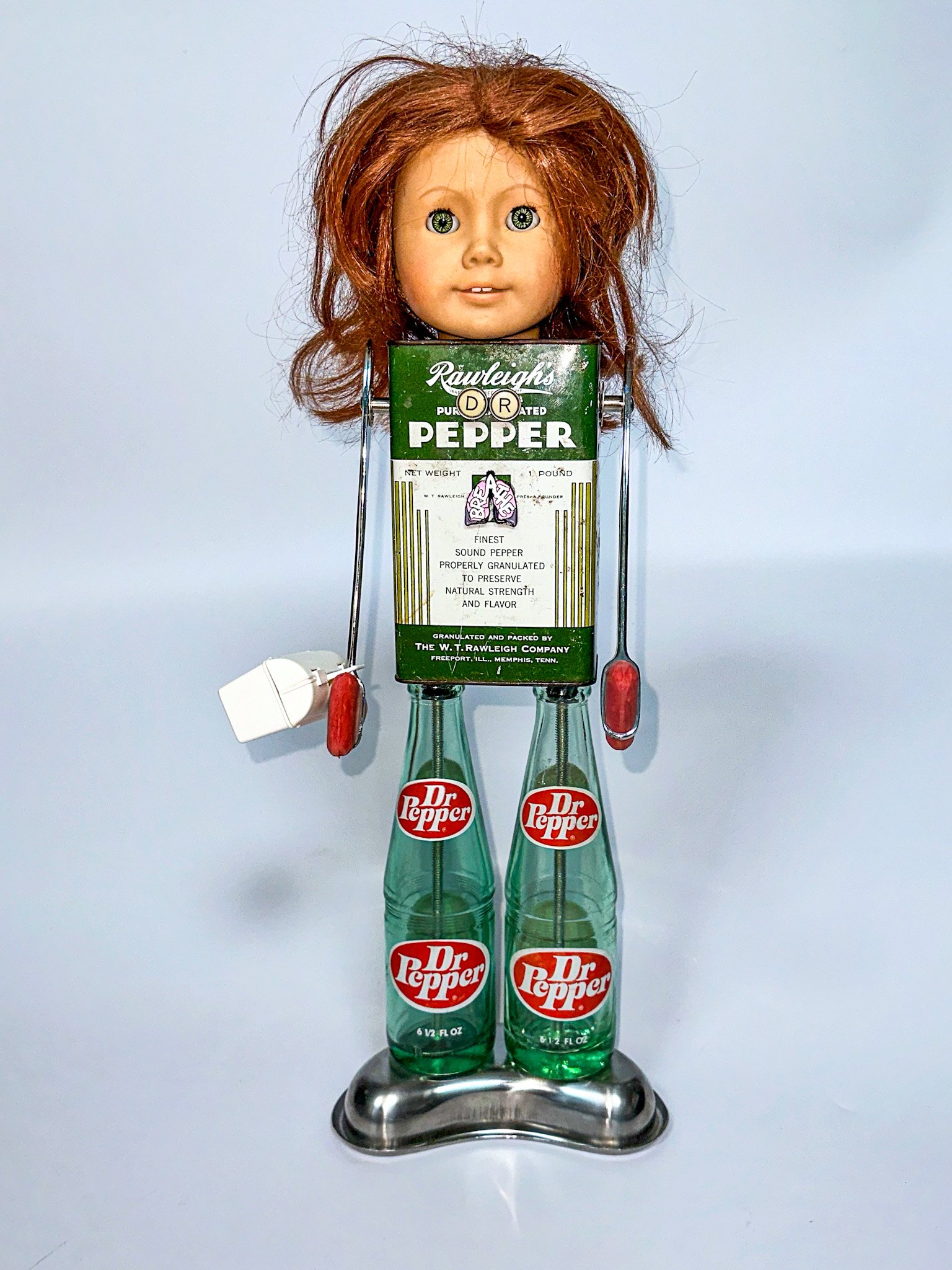 AVAILABLE. "Dr Pepper"
18" X 9" X 7"
1970’s Dr. Pepper glass bottles, Pepper tin, antique typewriter keys, reflex hammers, toy medical bag, toy stethoscope, doll head, emesis basin.
Free-standing or Wall-hanging.