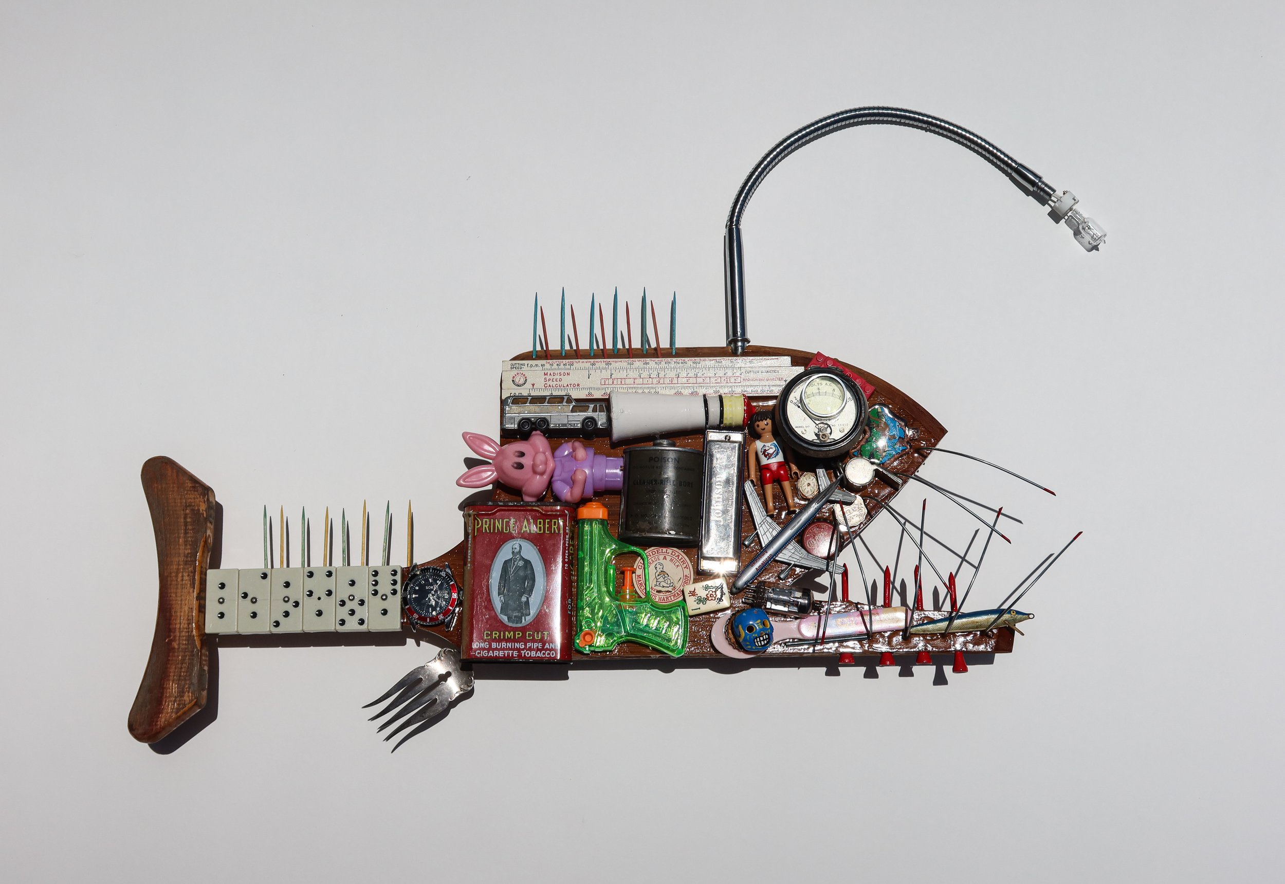 SOLD Found Fish #6; "Angler Fish". Broken pizza peel, wooden crutch end piece, hardware, dominos, vintage tins, toys, broken gooseneck lamp. 27"W X 15"T X 4"D.
.