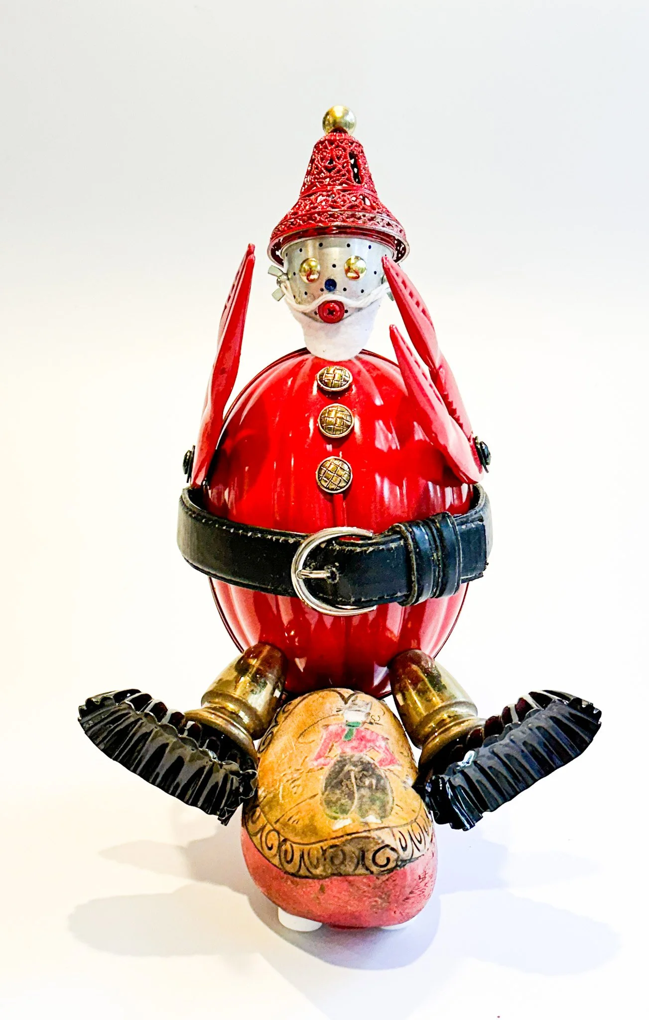 SOLD.  Santa Claws. 
Constructed of: 100 year old vintage Kreamer Melon Pudding Mold, Dutch wooden shoe, candy tins, brass chandelier parts, brass buttons, lobster claw crackers, old leather belt, loose tea leaf strainer, furniture nails, bell orname