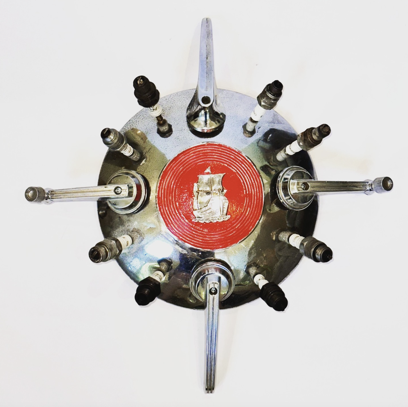 SOLD.
"Le Assemblage Pour Le Garage" aka "Garage Wreath" To be exhibited at The Old Sculpin Gallery, Dec 8 & 9, for the Christmas in Edgartown show.
17" X 16" X 3"
Hubcap from a 1940’s Plymouth, vintage window cranks, old spark plugs.
Appearing at